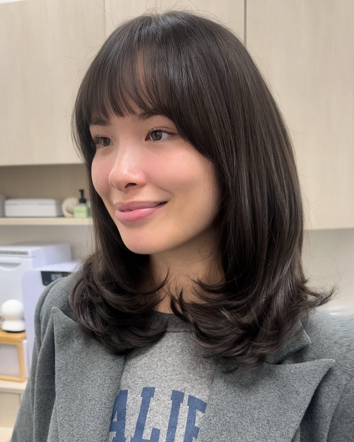 Glossy Dark Shoulder-Length Cut with Soft Blunt Bangs and Flipped Ends