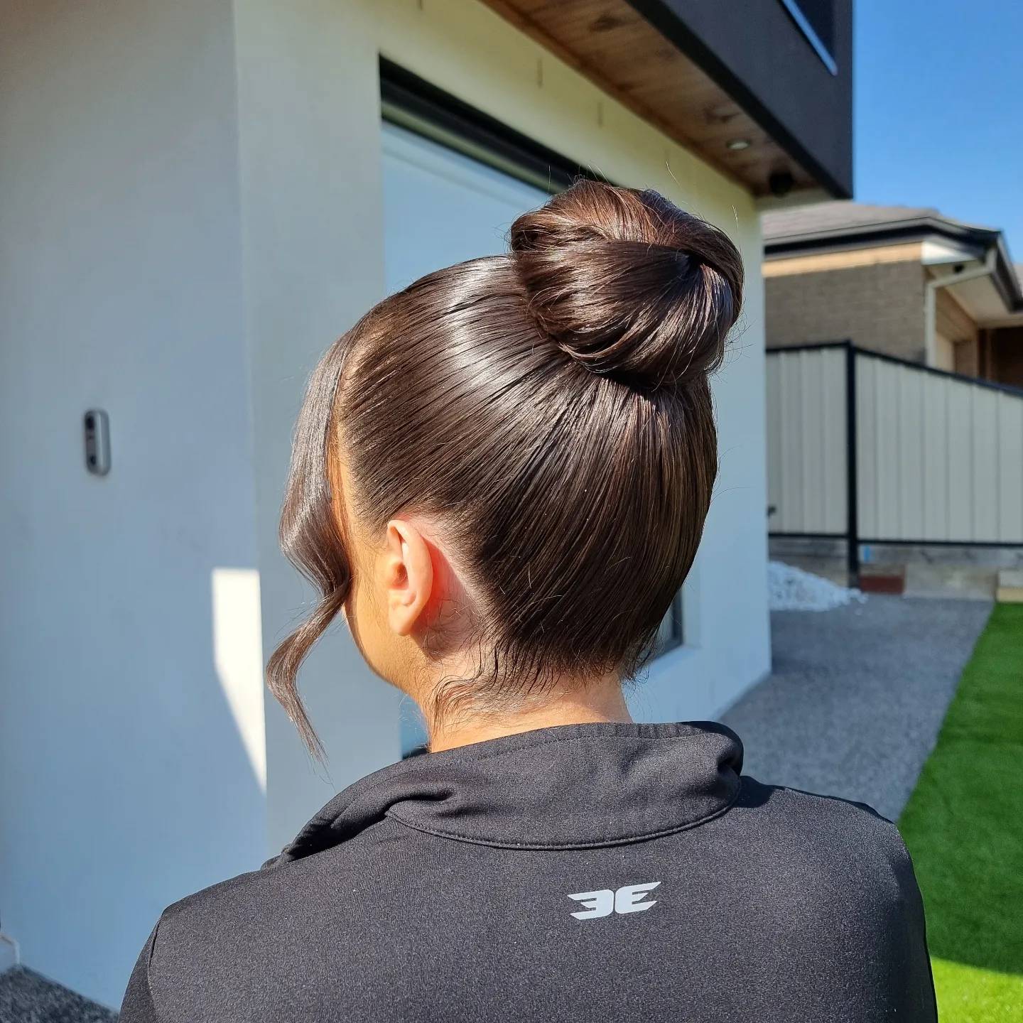 Smooth high bun on brunette hair photographed outdoors