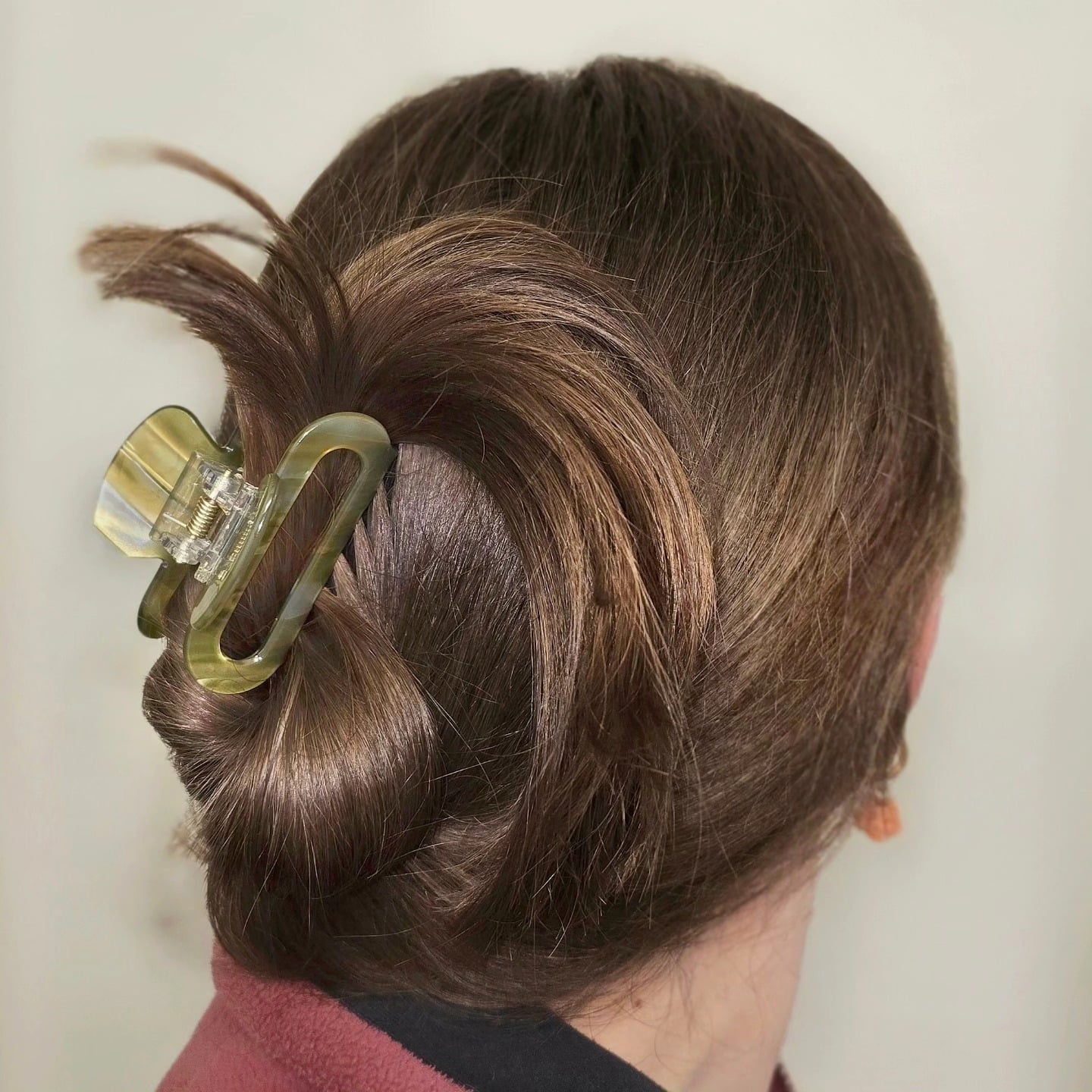 Brown hair in a French twist secured with olive claw clip
