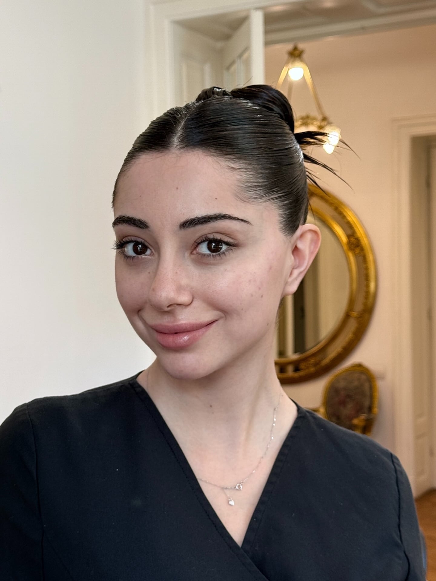 Slicked dark hair pulled into a small sprouting top knot