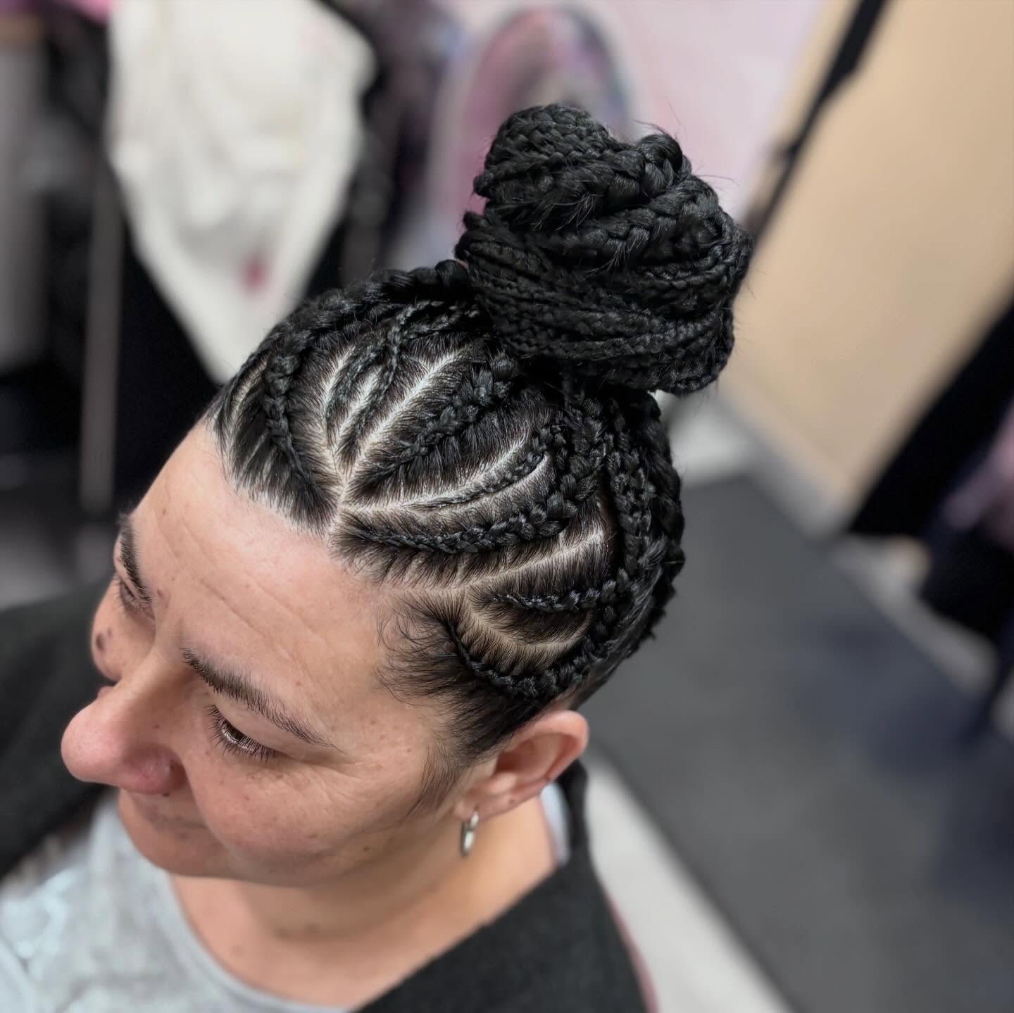 Intricate stitch cornrows gathered into a braided top knot