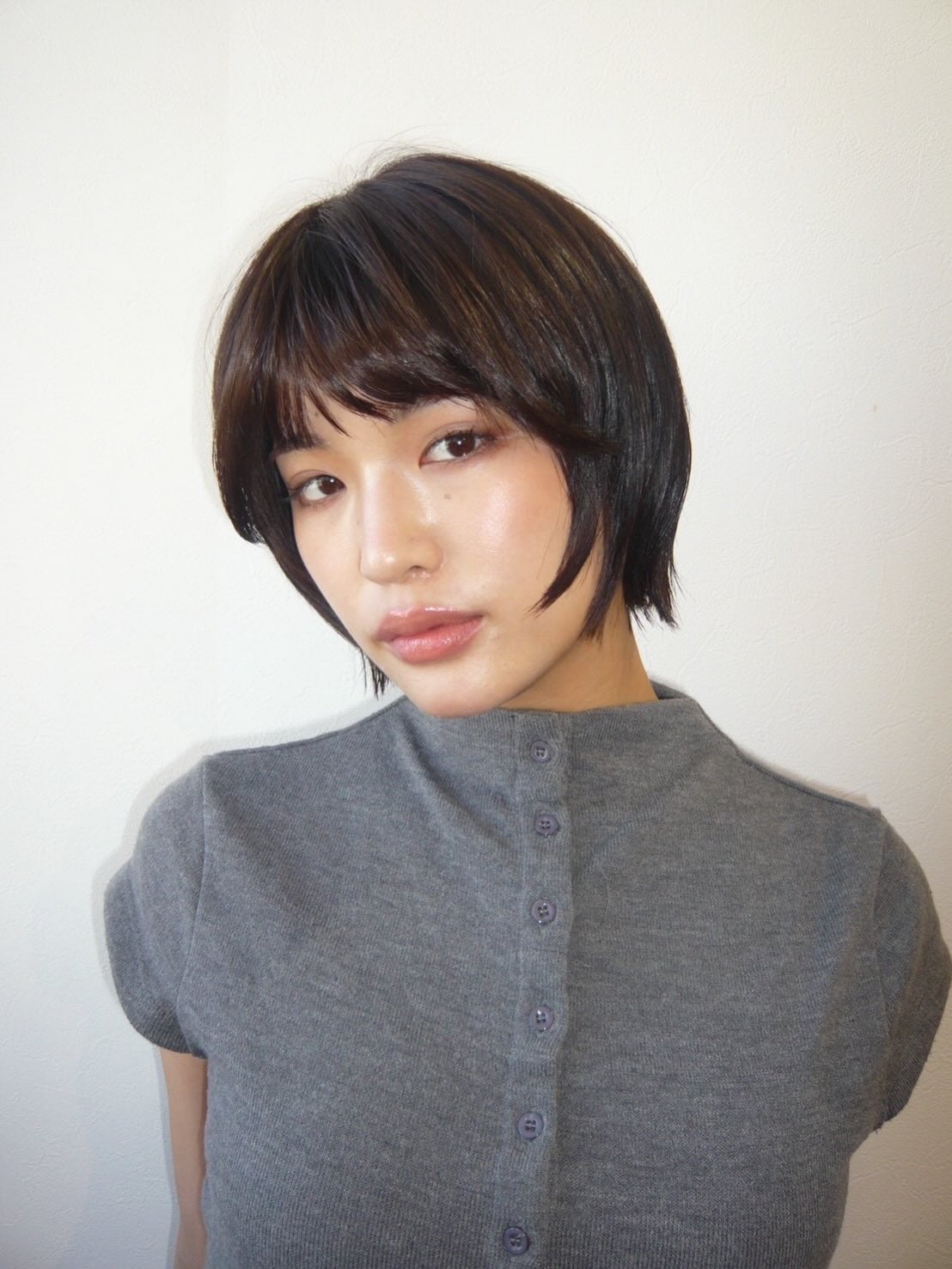 Short dark tapered bob with soft fringe and ear tuck