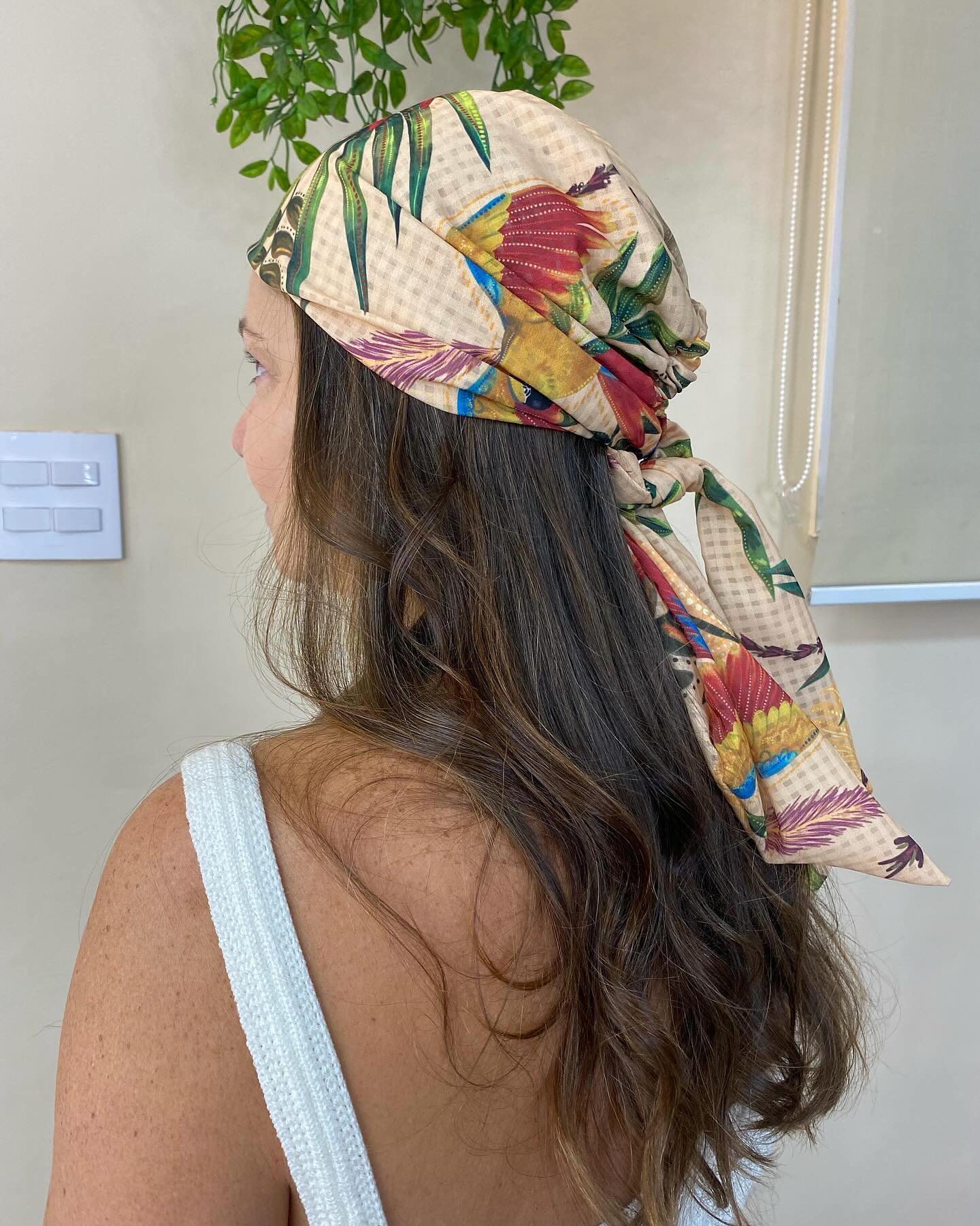 Floral tropical scarf tied over long dark wavy hair