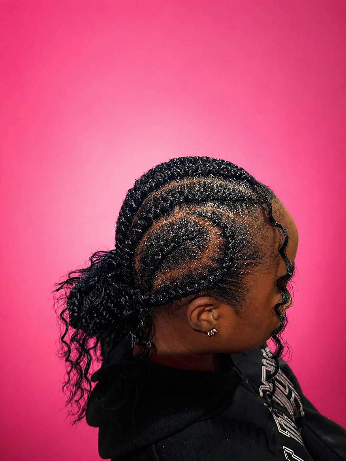 Cornrow swirl pattern with curly ponytail at nape
