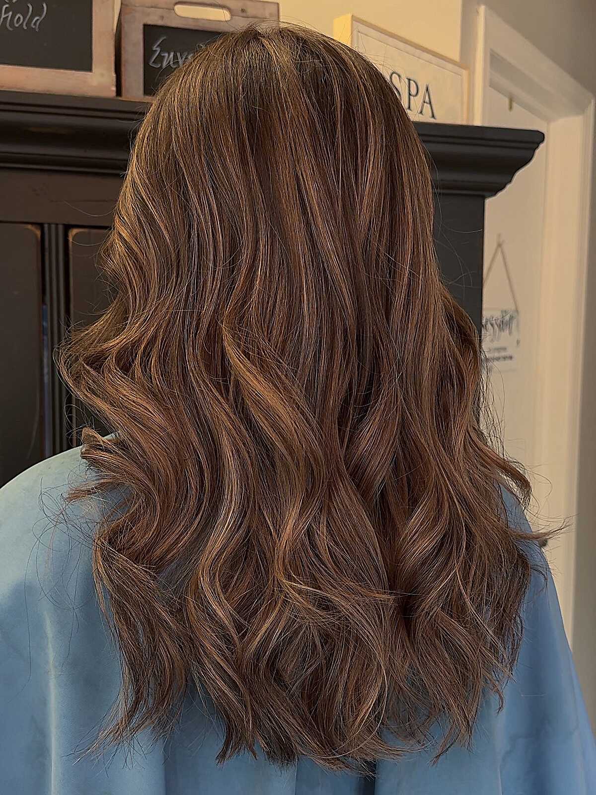 Warm brown hair with cinnamon-toned highlights and waves