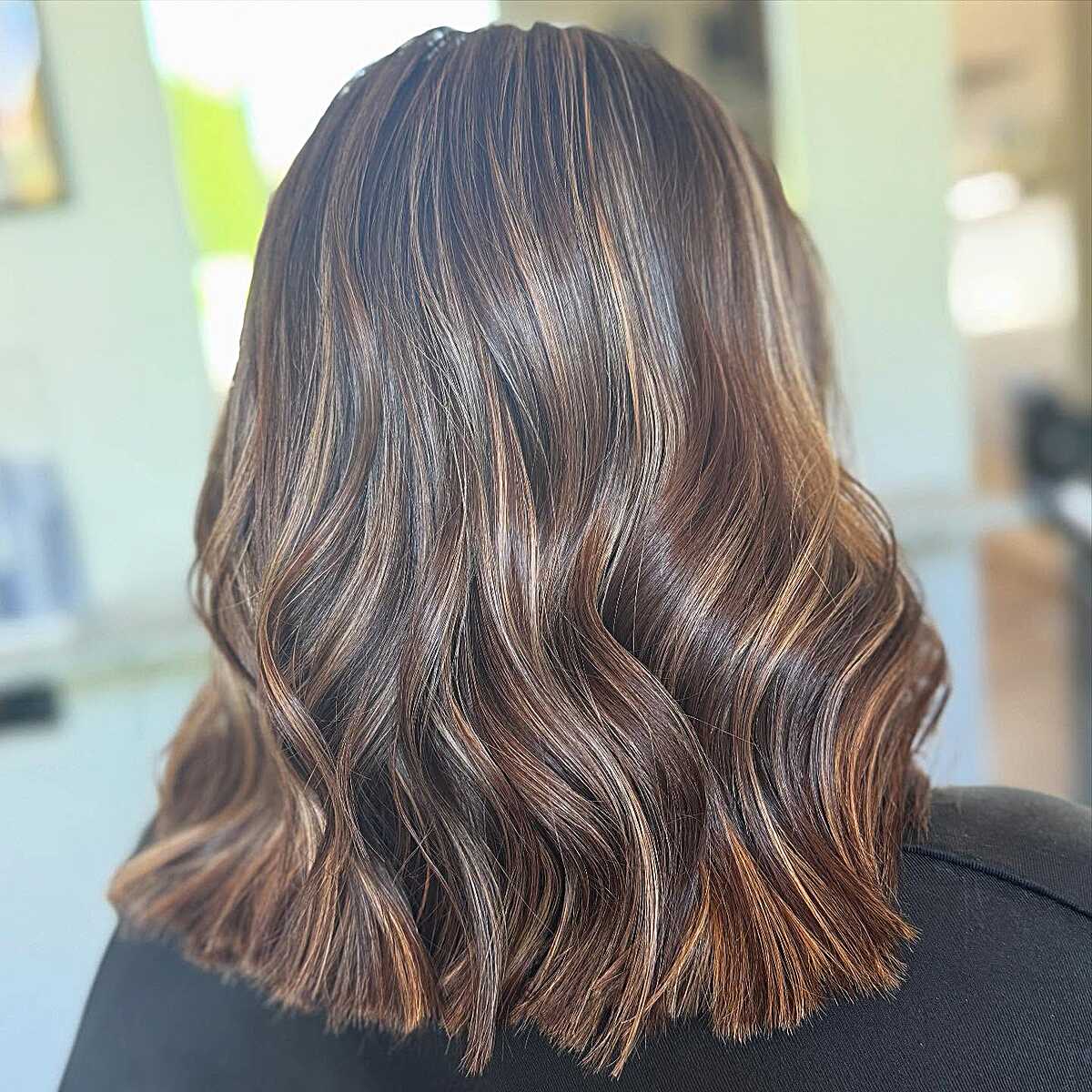 Wavy brunette lob with copper and caramel highlights