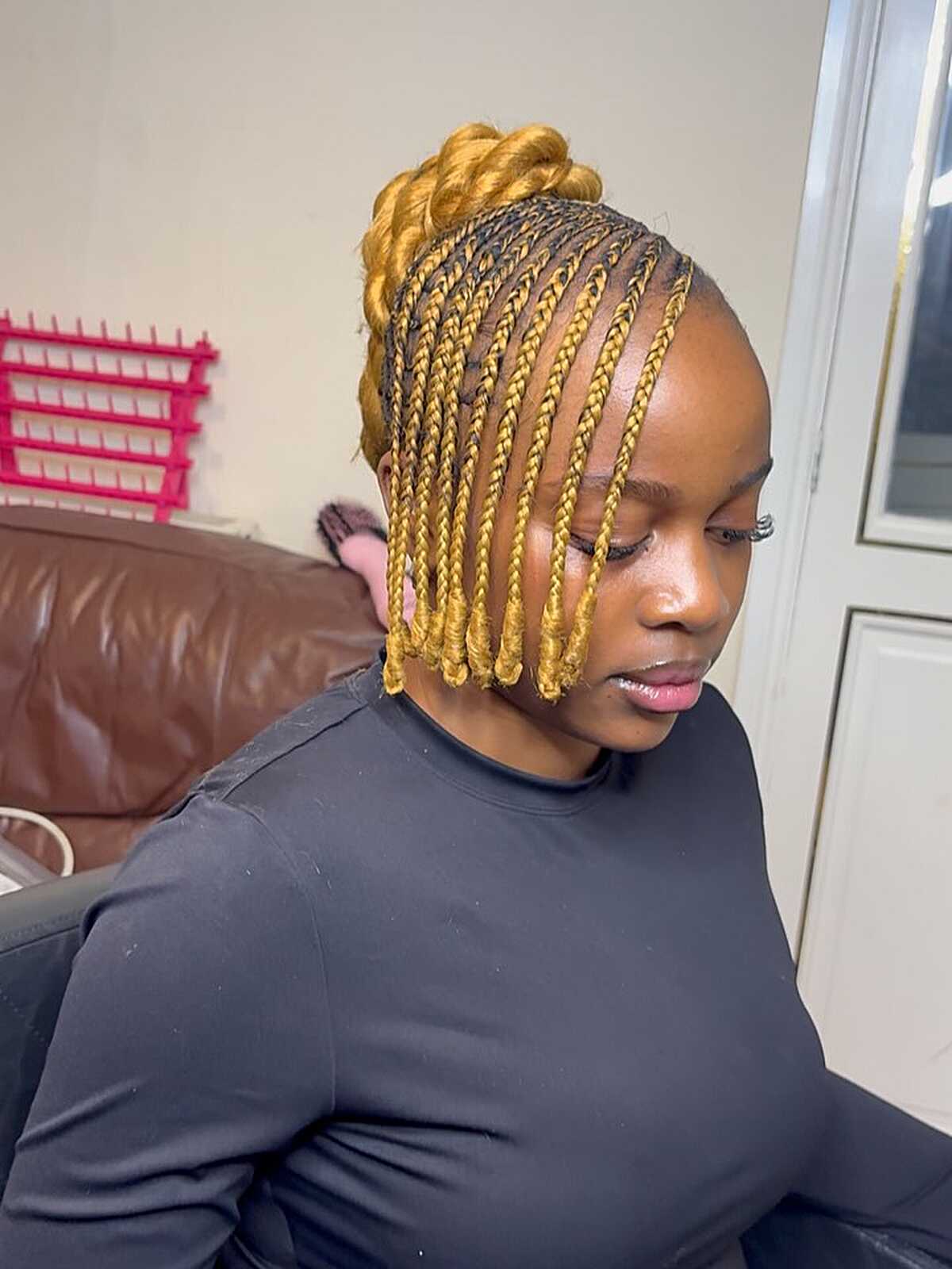 Golden blonde knotless braids styled in a top bun