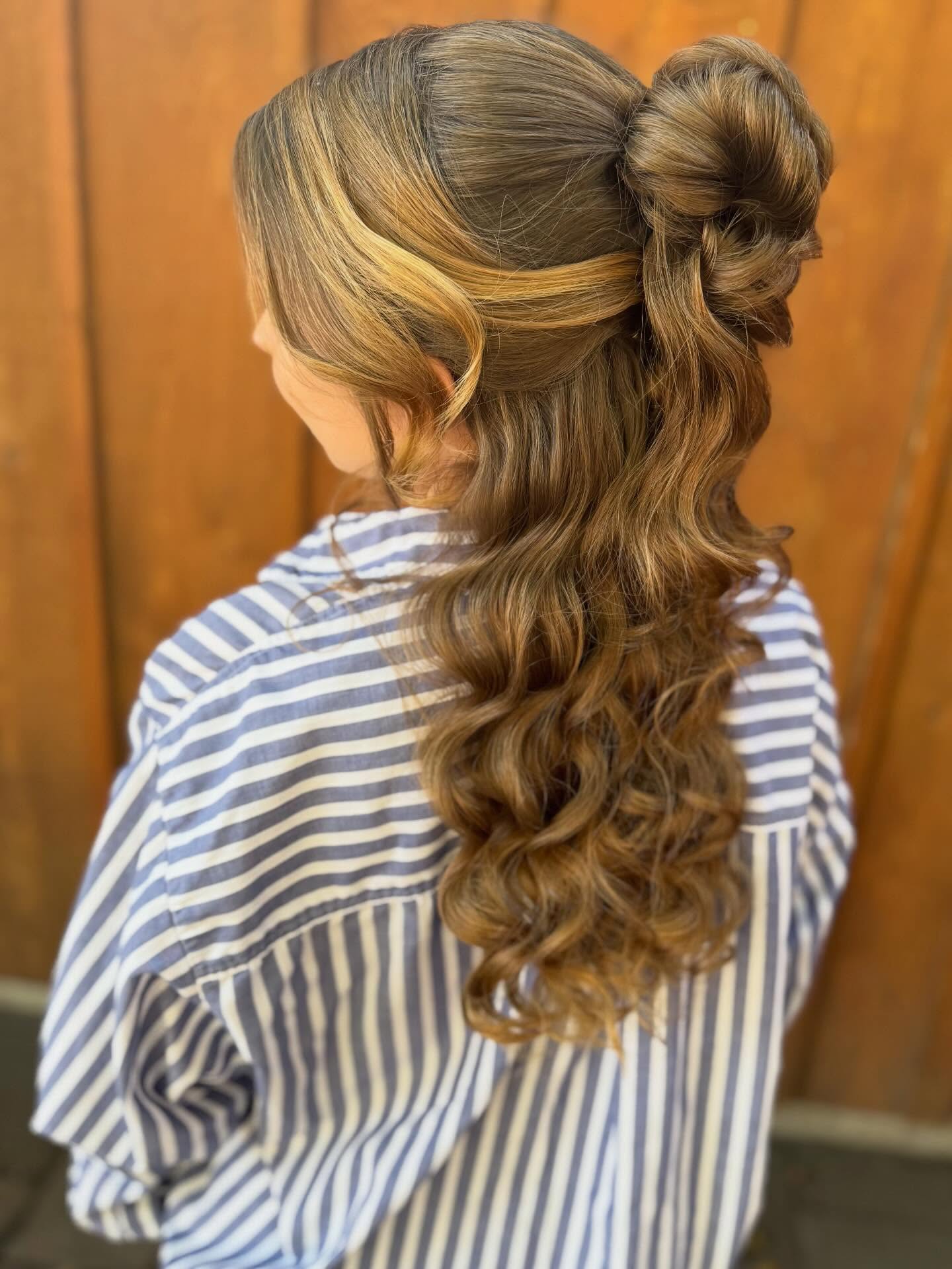 Half-up twisted bun with long curled ends on brunette