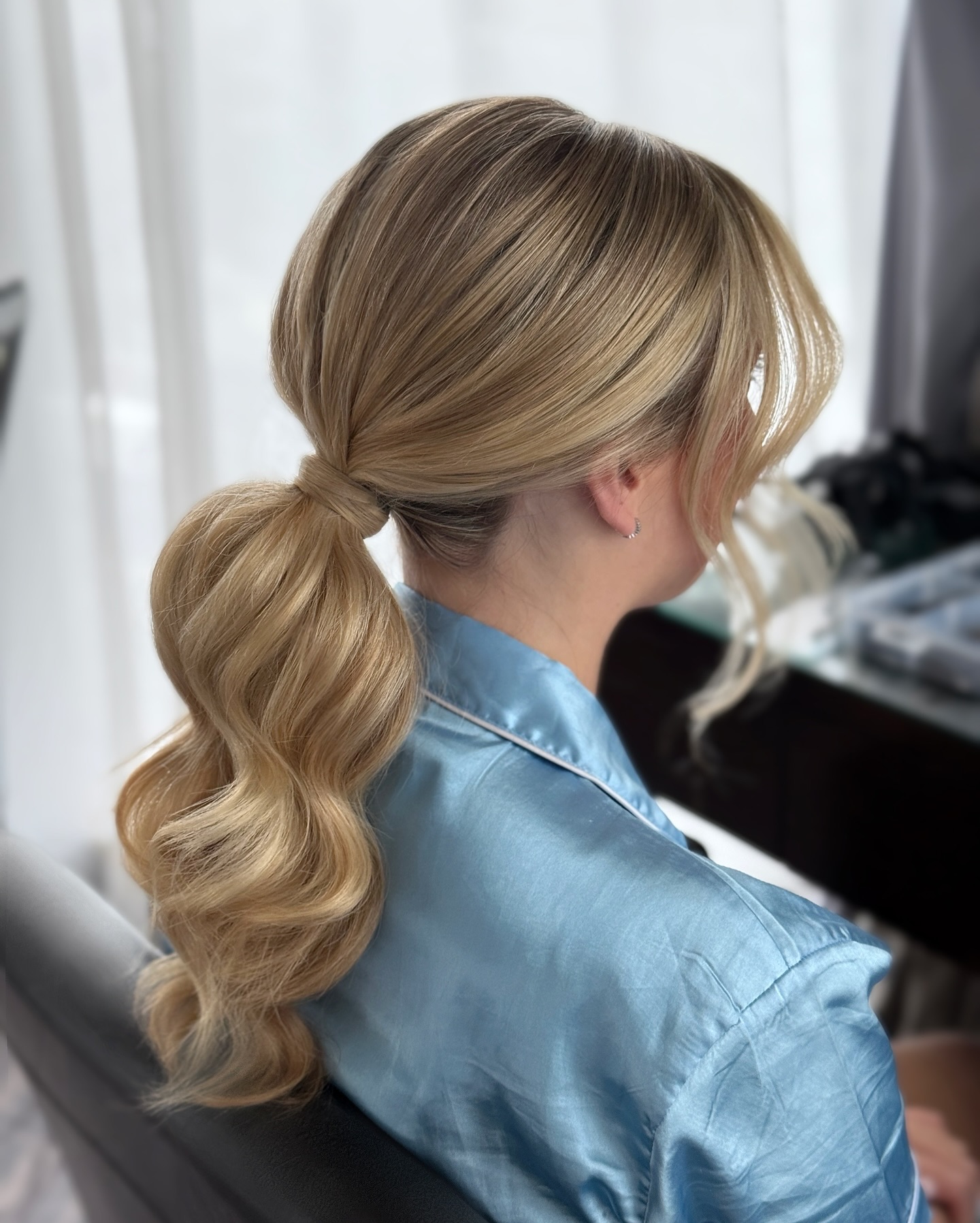 Low wrapped ponytail with soft blonde waves