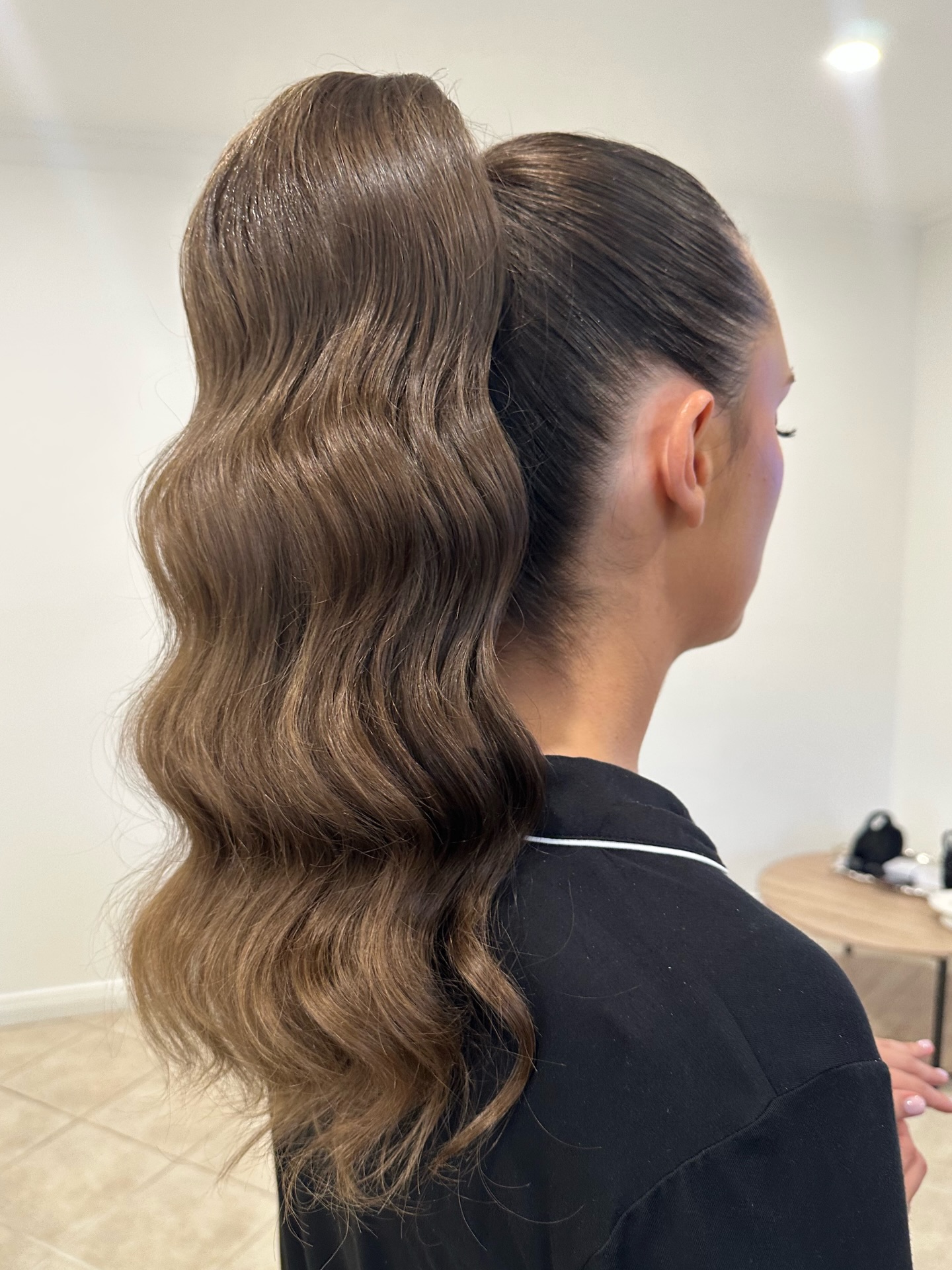 Sleek high ponytail with deep body waves on brunette