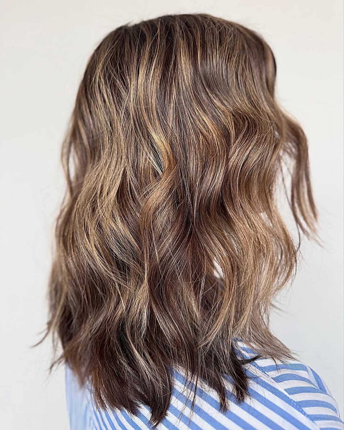 Medium wavy brunette with sun-faded golden highlights
