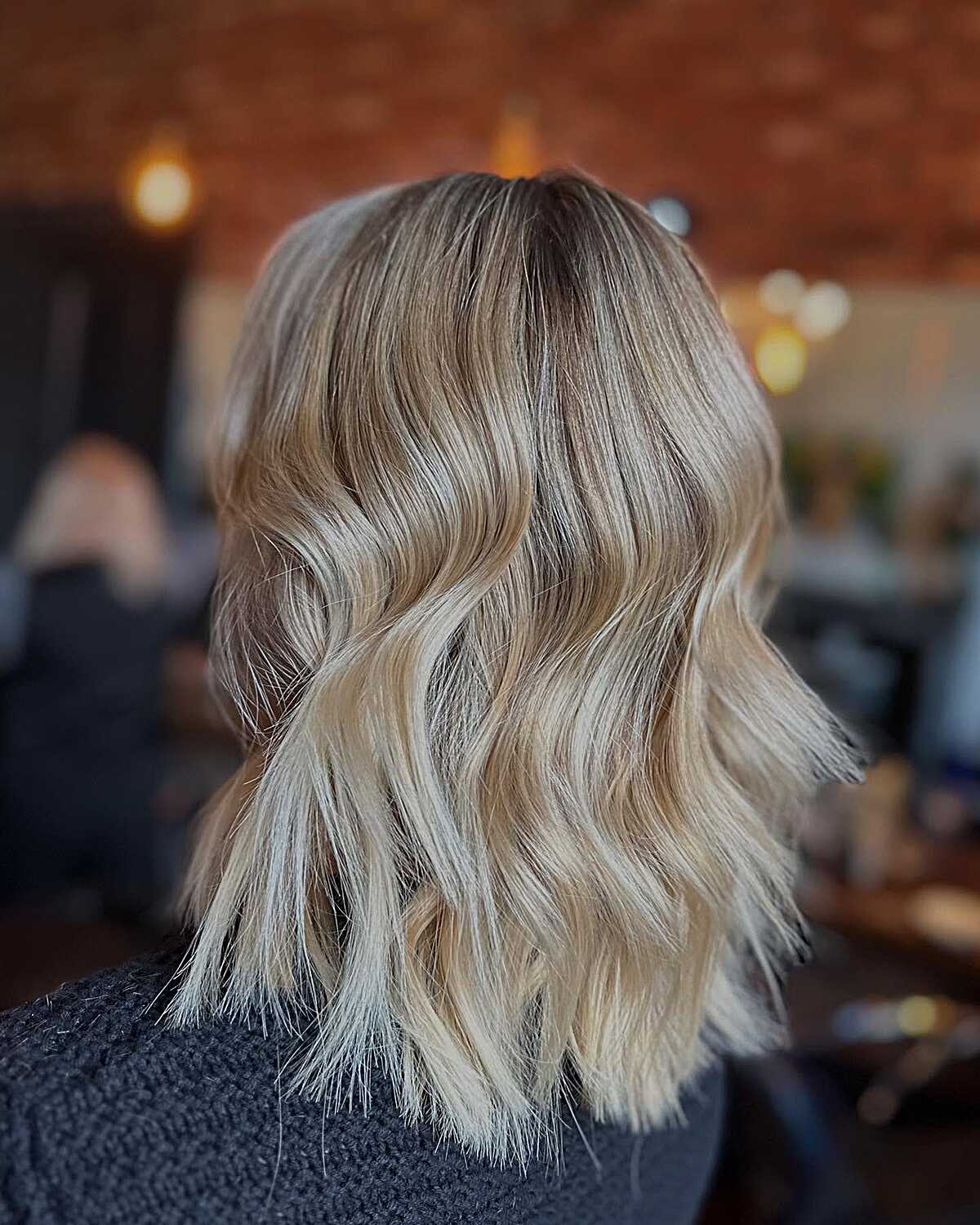 Textured blonde lob with dark shadow root and choppy waves