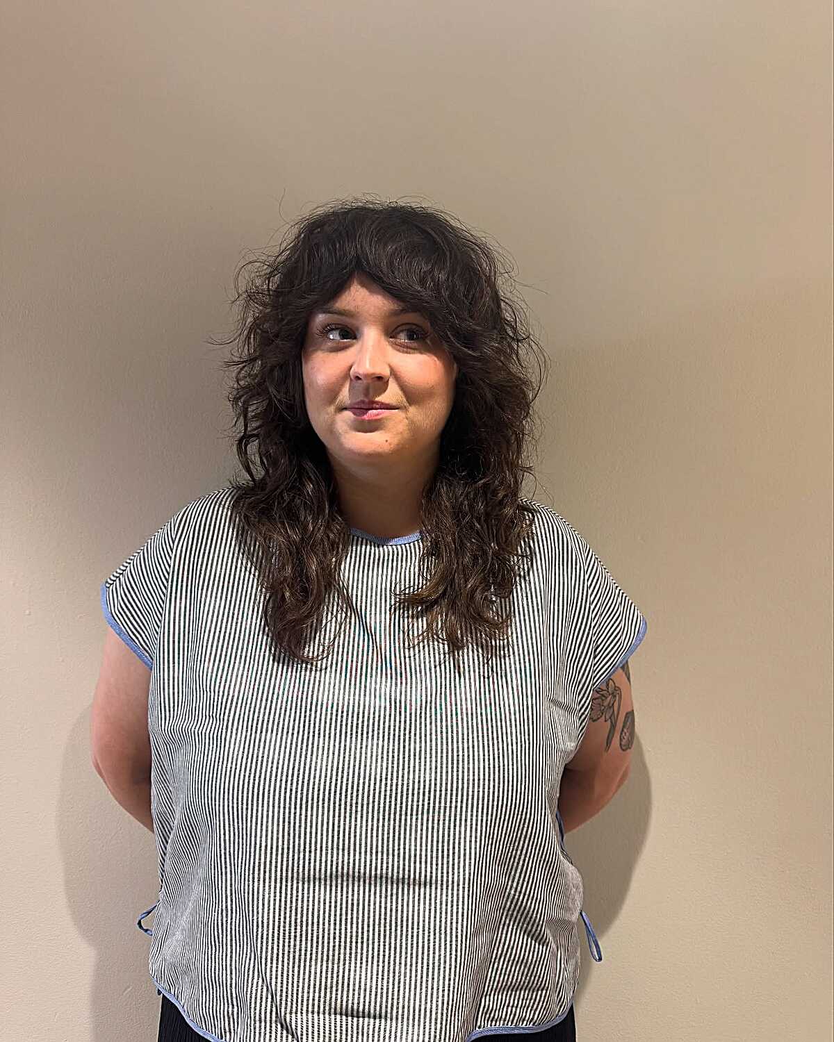 Dark curly shoulder-length shag with wispy bangs