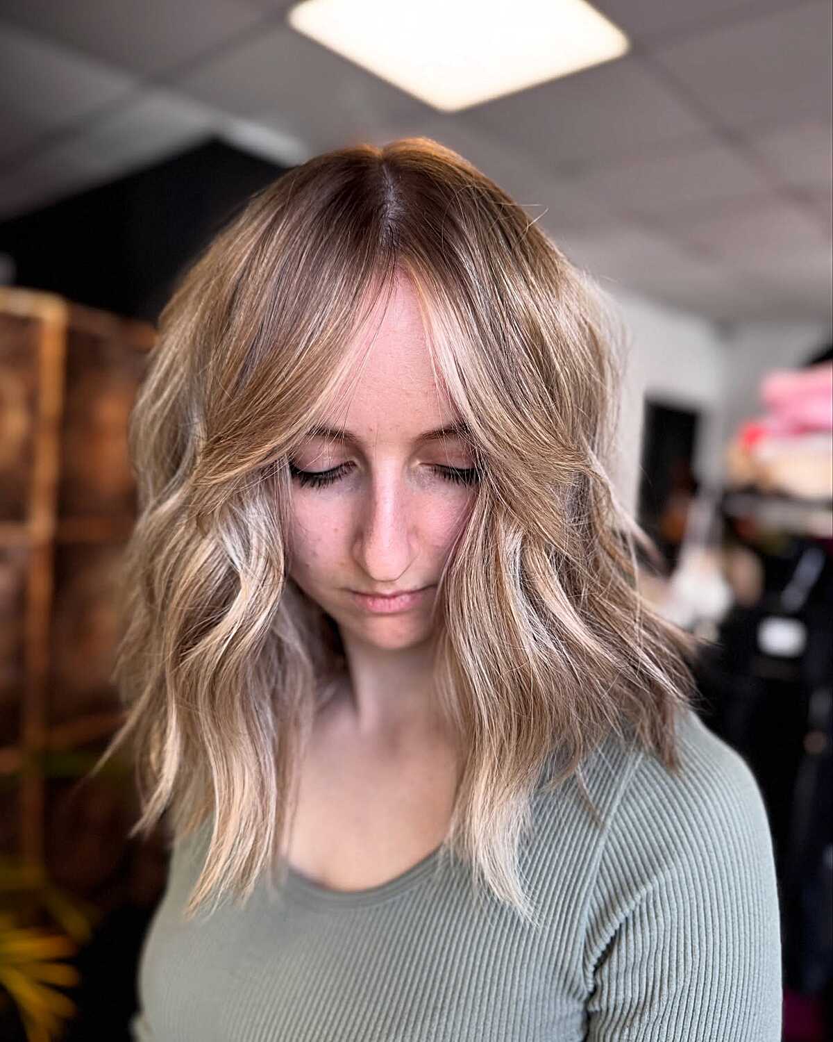 Sandy blonde wavy lob with soft curtain bang wisps