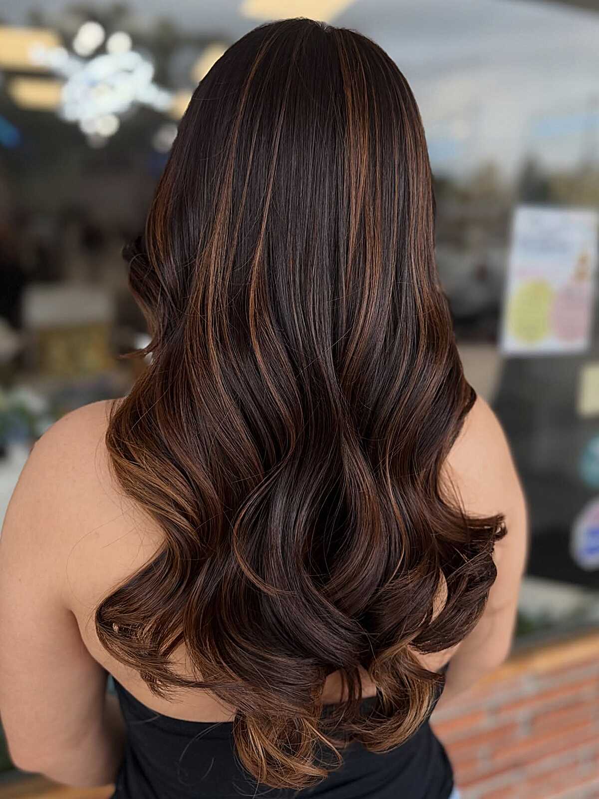 Long dark brown hair with caramel balayage and curled ends