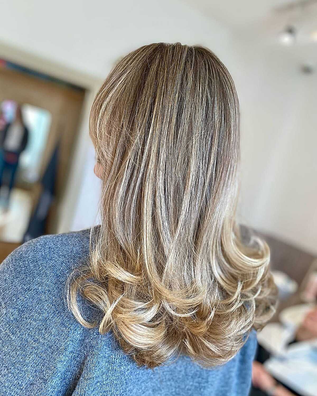 Layered blonde balayage with curled blowout styling