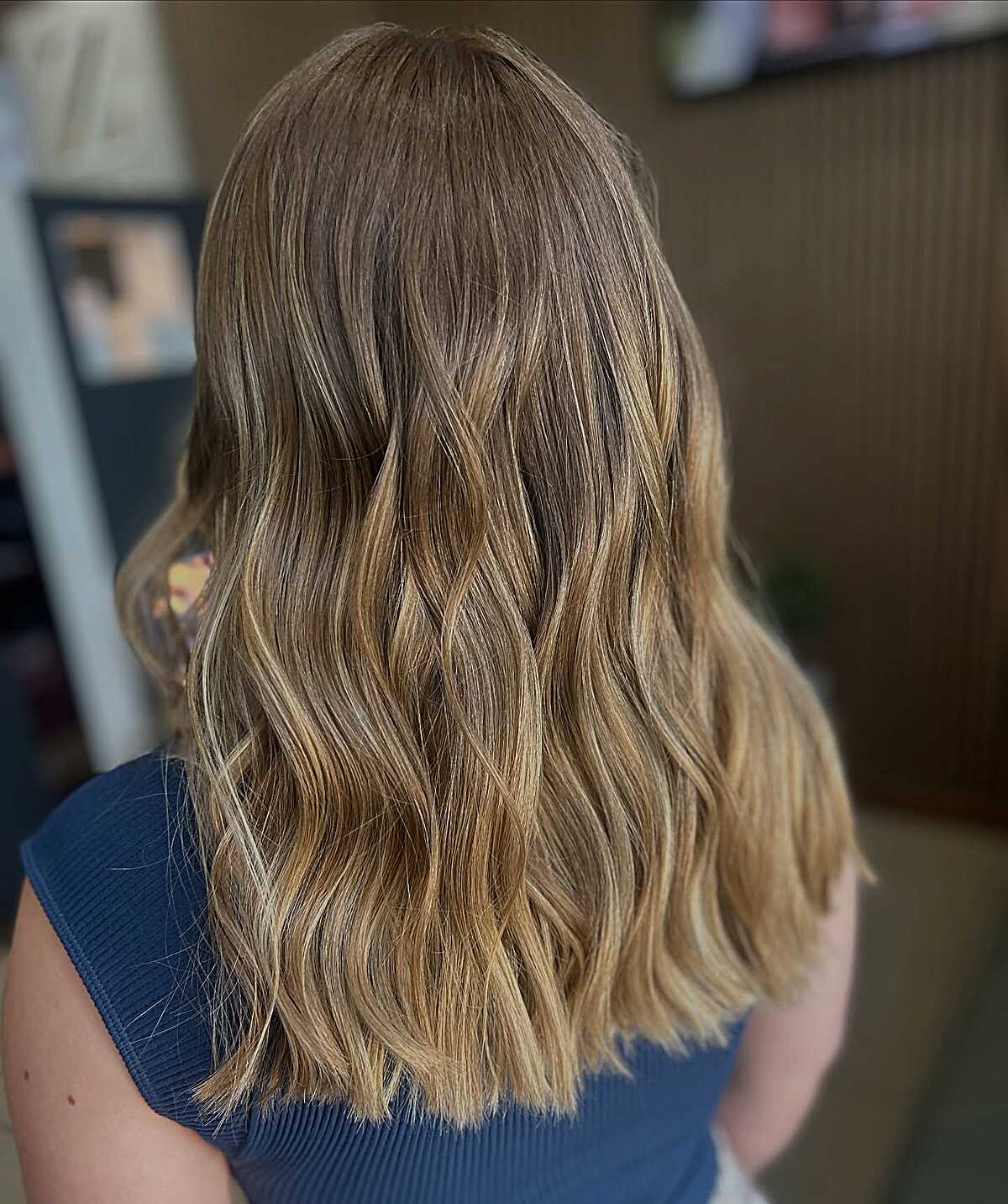 Mid-length honey wheat blonde balayage with soft waves