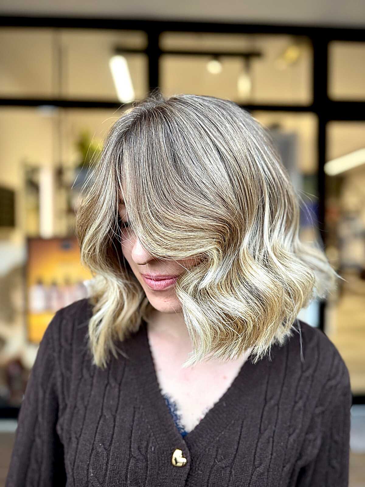 Wavy blonde lob with dark roots and face framing