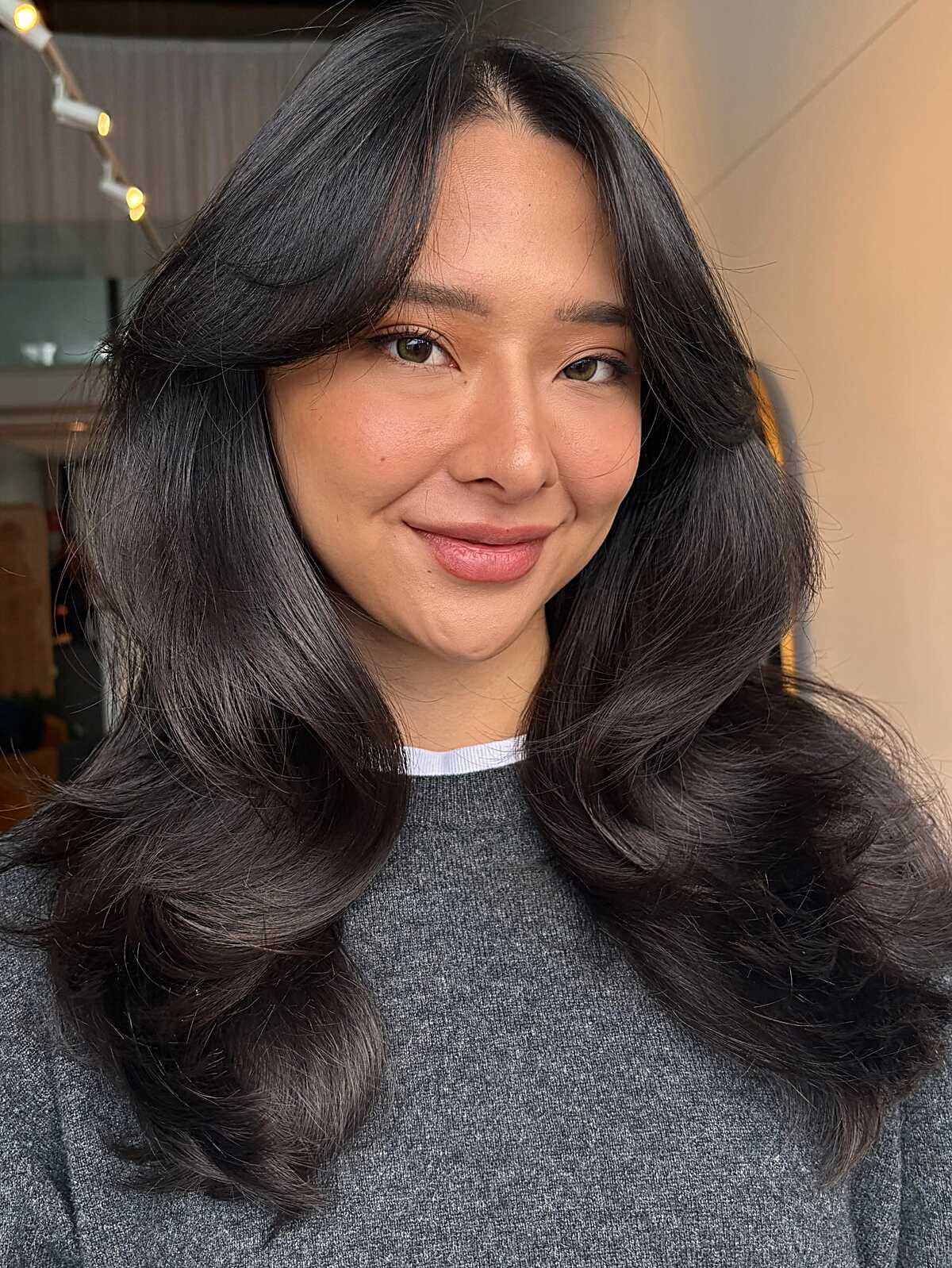 Glossy black curled long layers with round curtain bangs