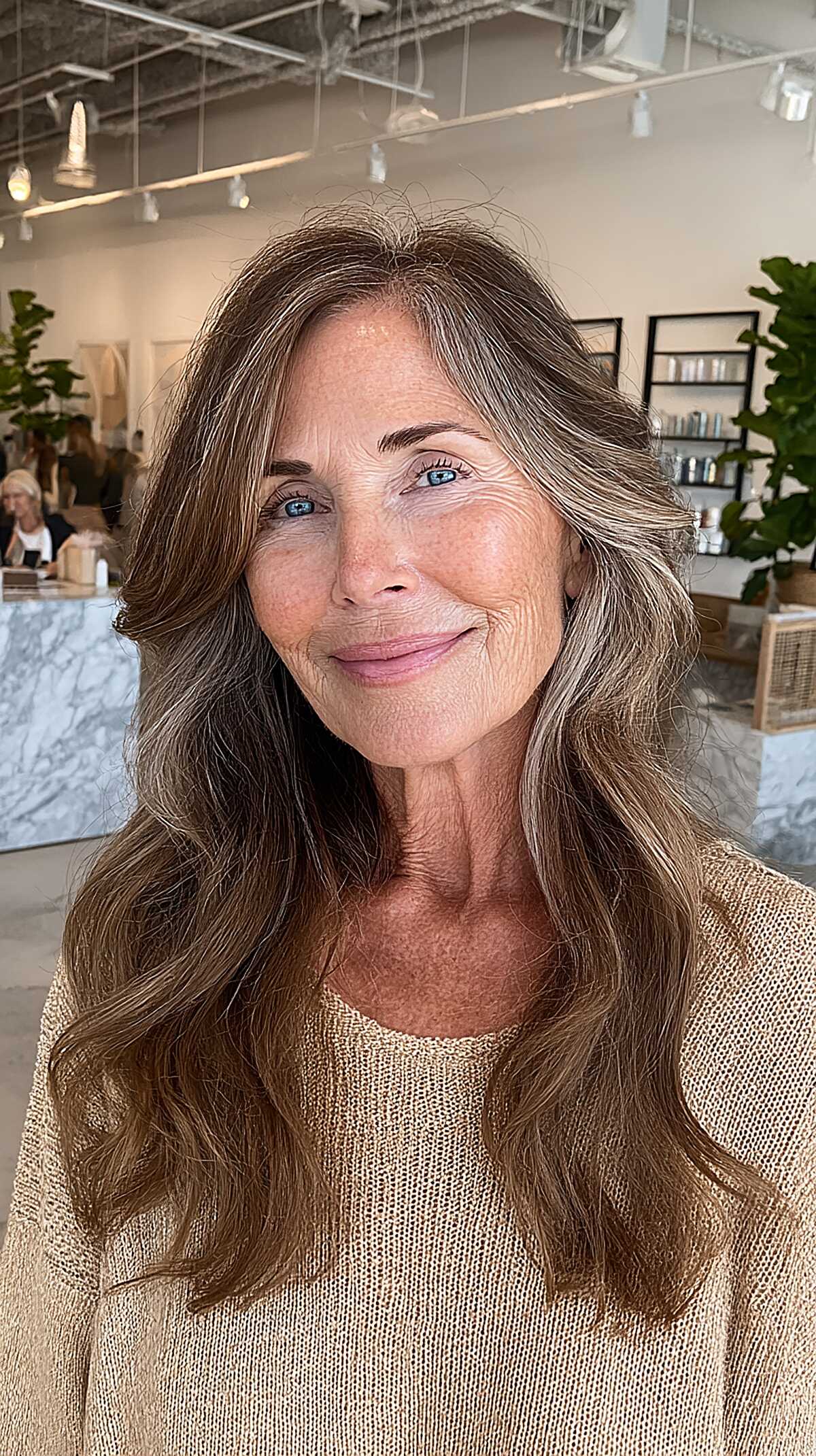Long wavy brown hair with natural gray streaks framing face