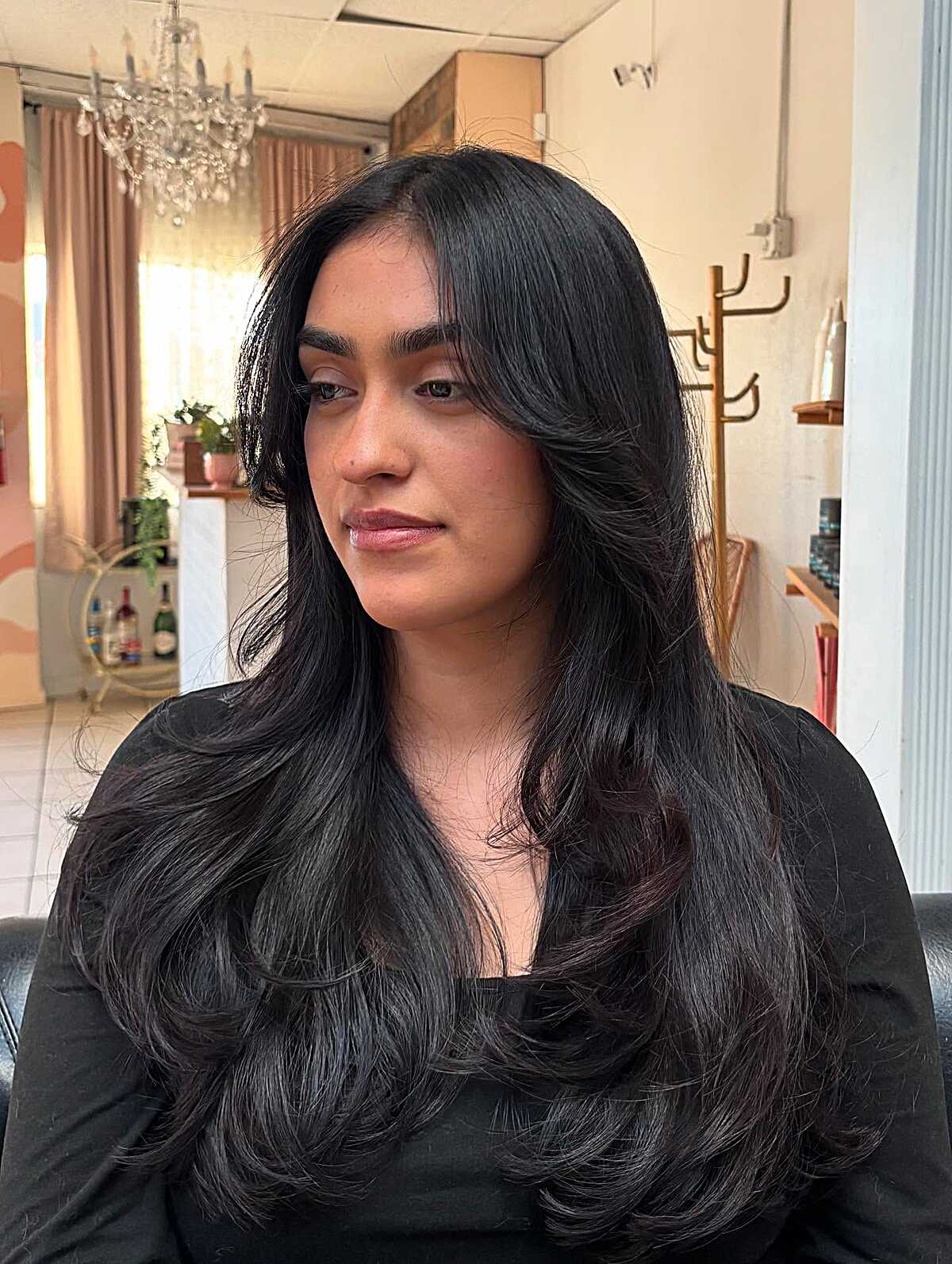 Long jet black layered hair with curtain bangs and soft bend