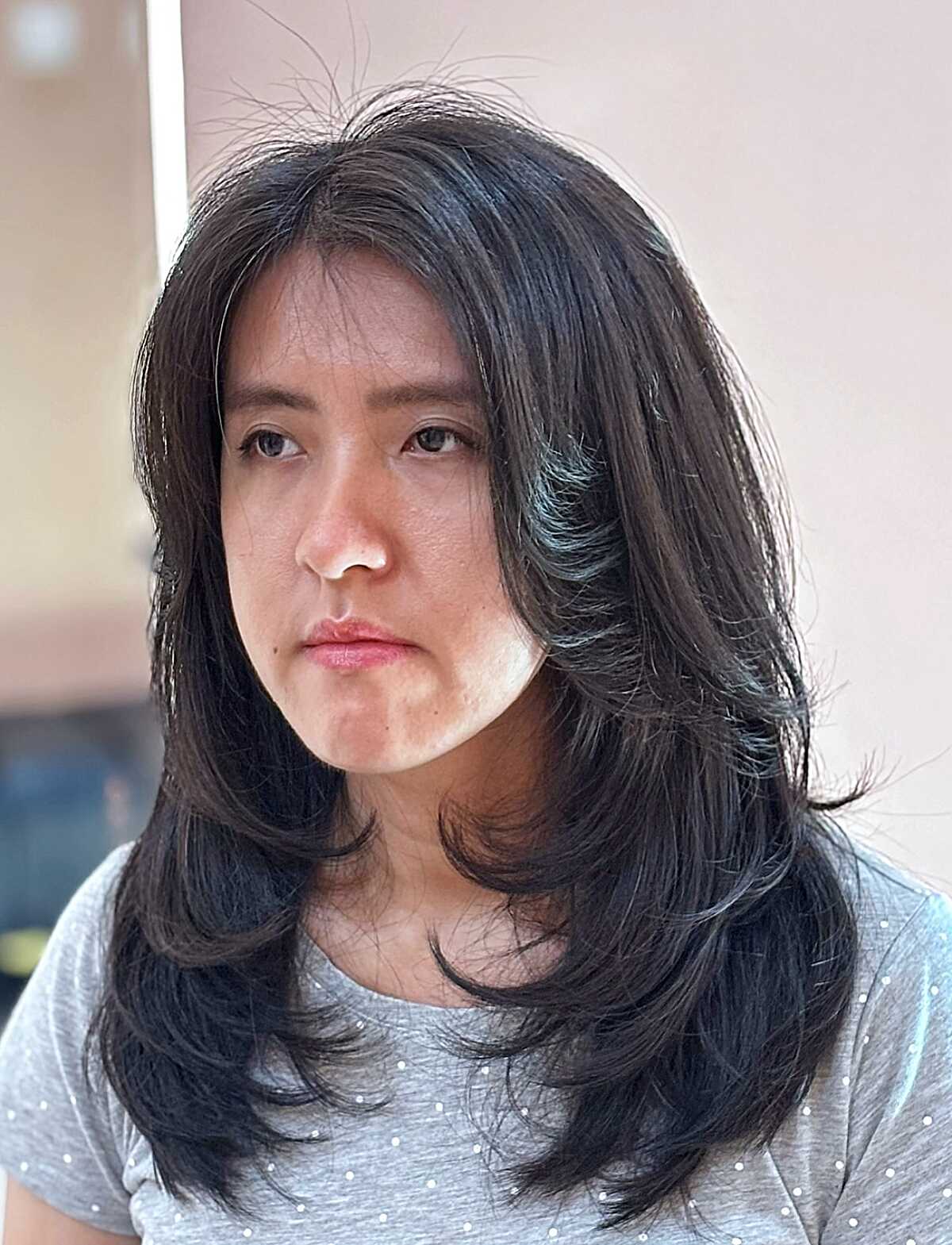 Layered black mid length hair with curtain face frame