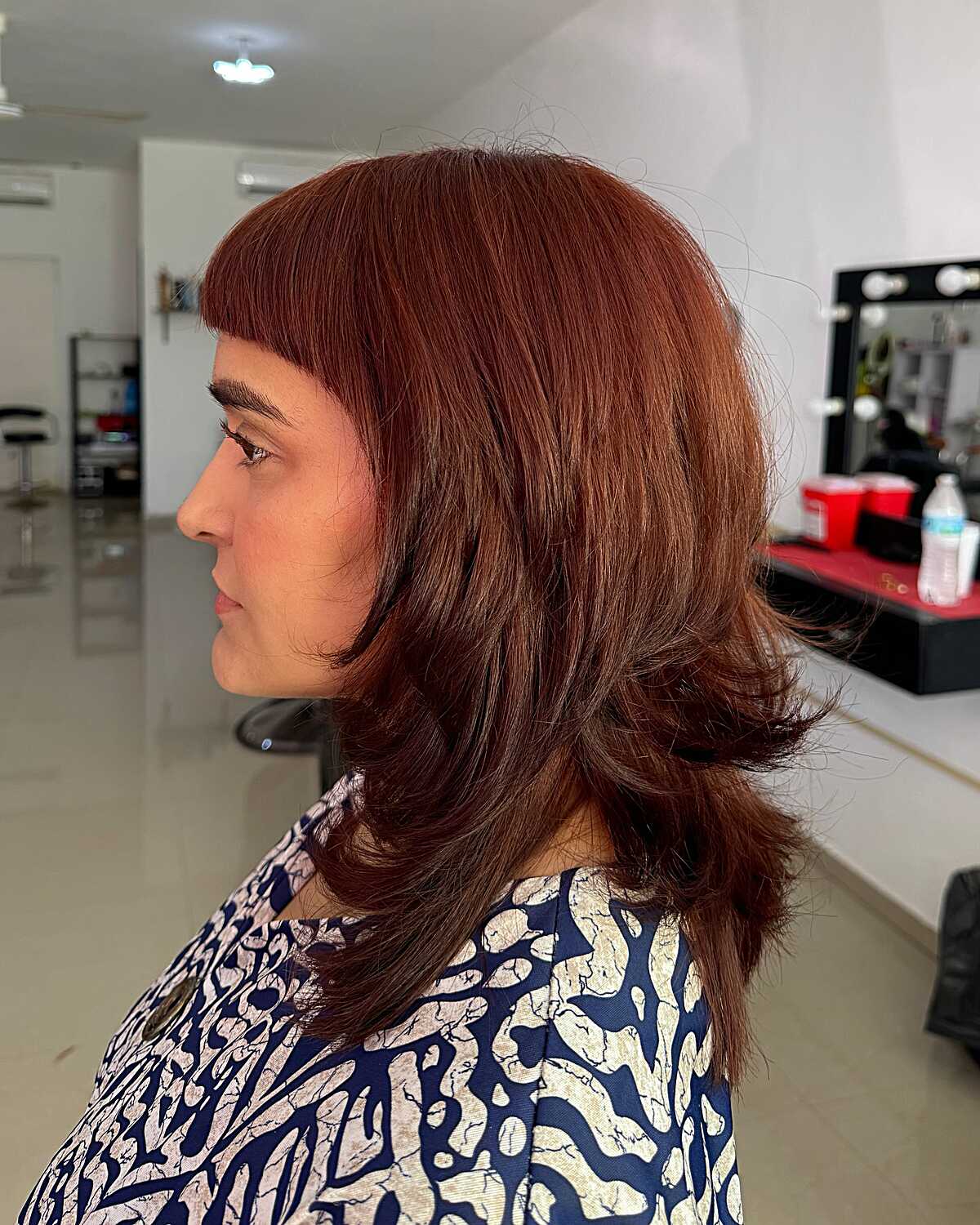 Auburn mid length butterfly cut with short bangs