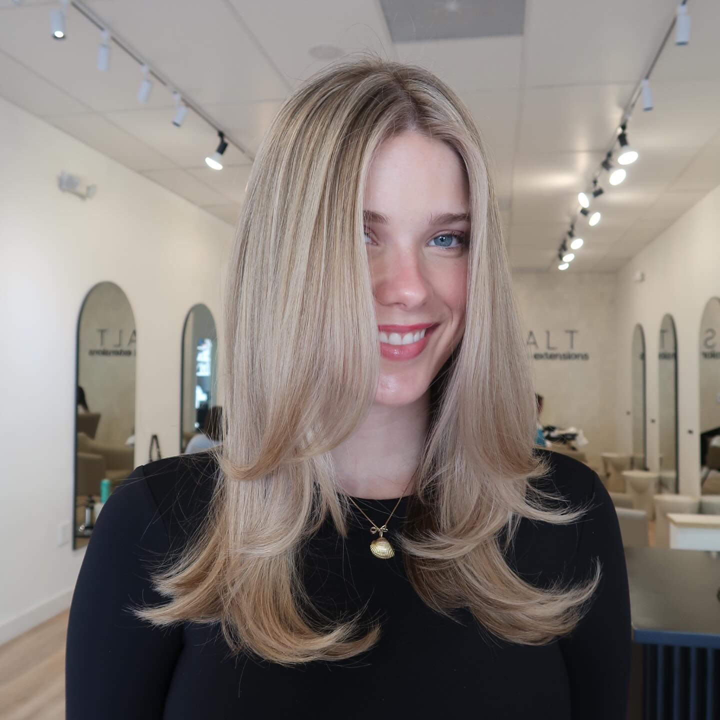 Medium blonde layered hair with flipped ends and side part