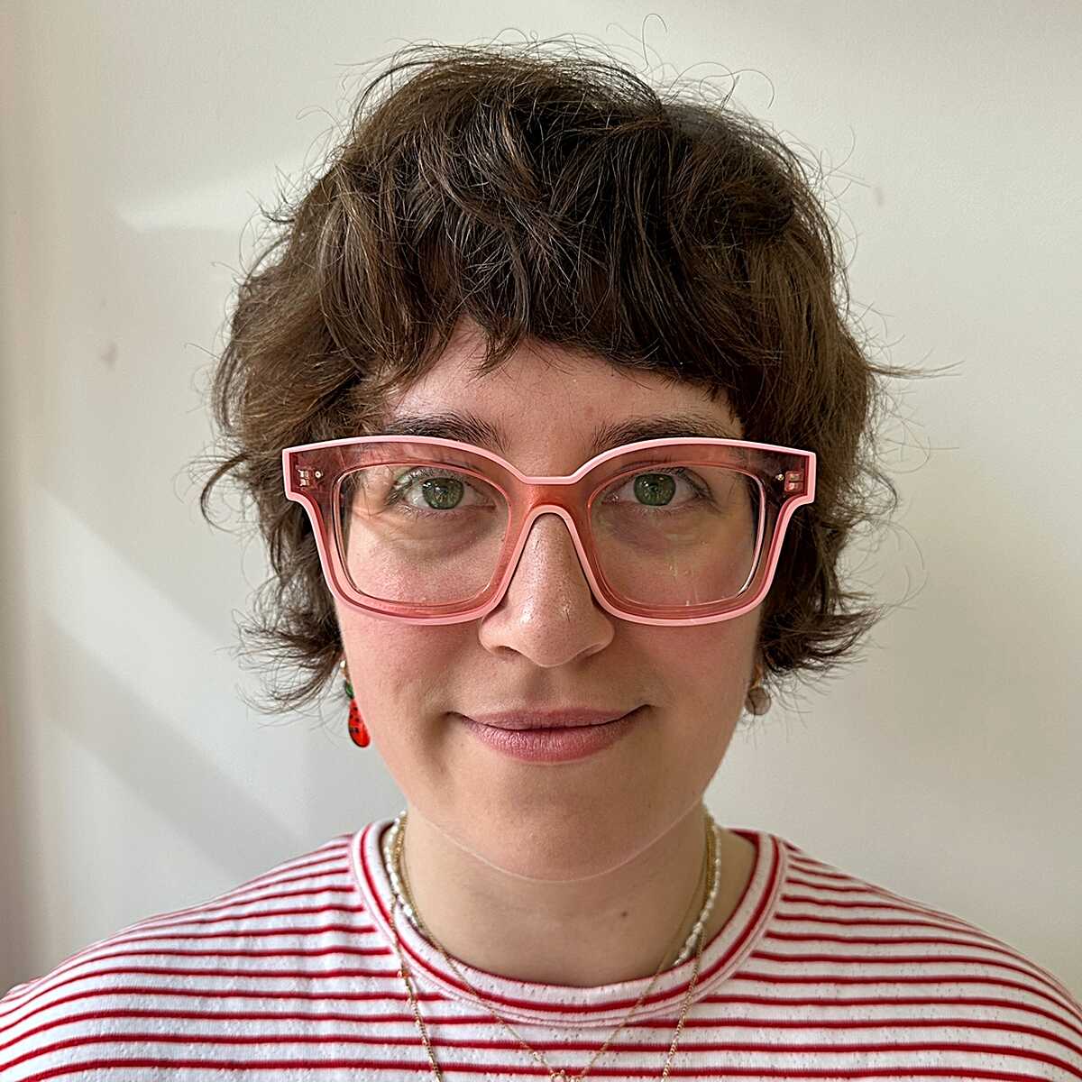 Curly brown pixie with playful fringe and pink glasses