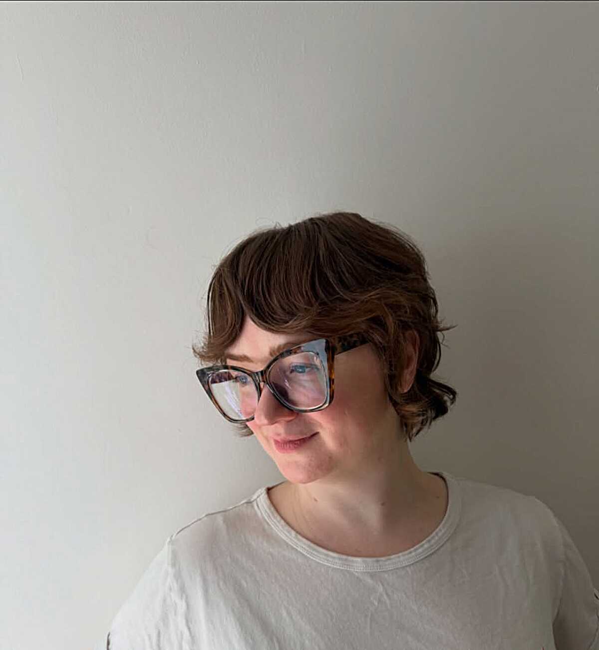 Chestnut wavy pixie bob with baby bangs and glasses