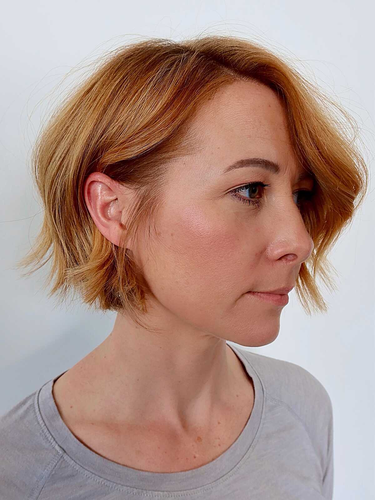 Strawberry blonde chin-length bob tucked behind one ear