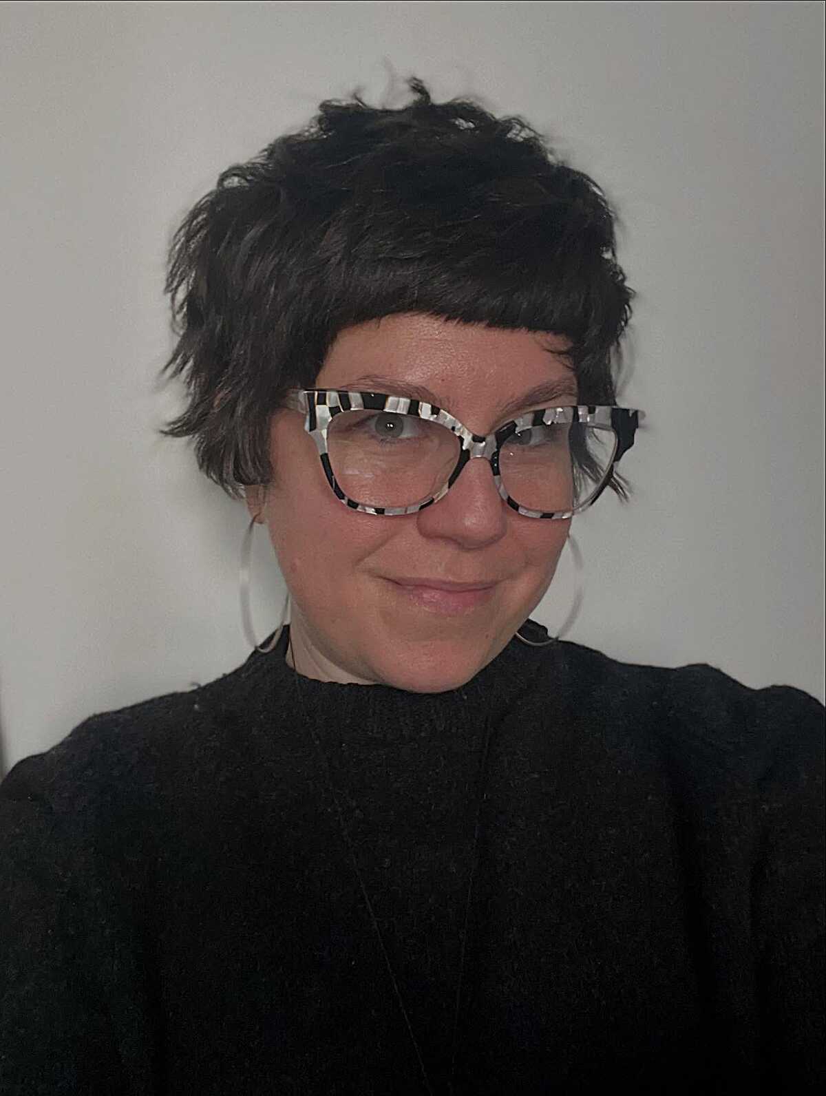 Tousled dark pixie cut with patterned statement glasses