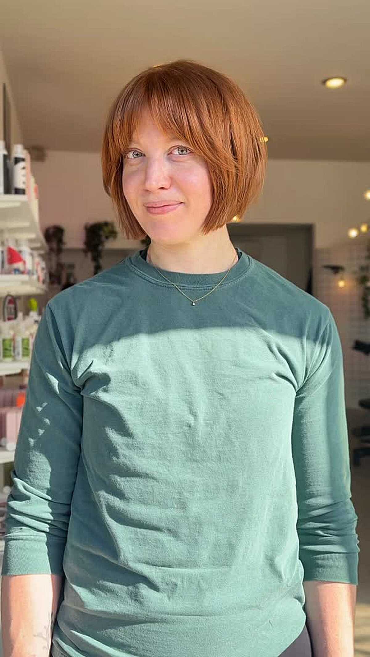 Chin-length warm copper bob with soft wispy bangs