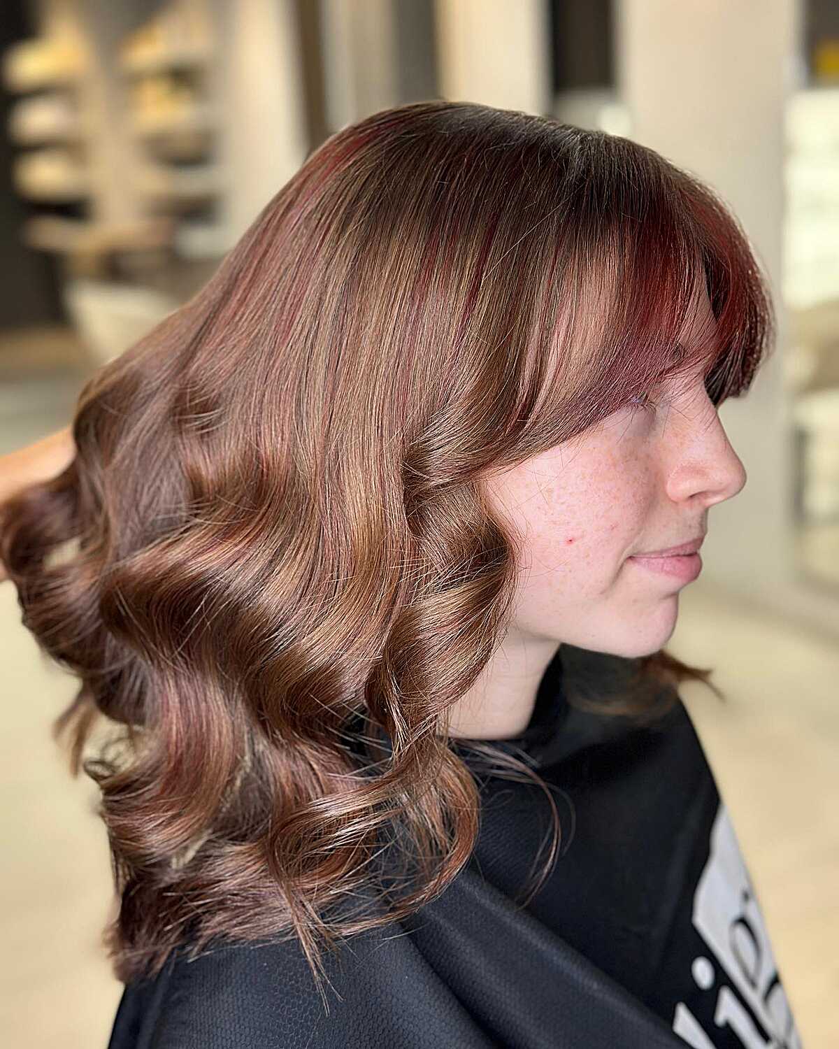 Medium brown curled hair with auburn highlights and bangs