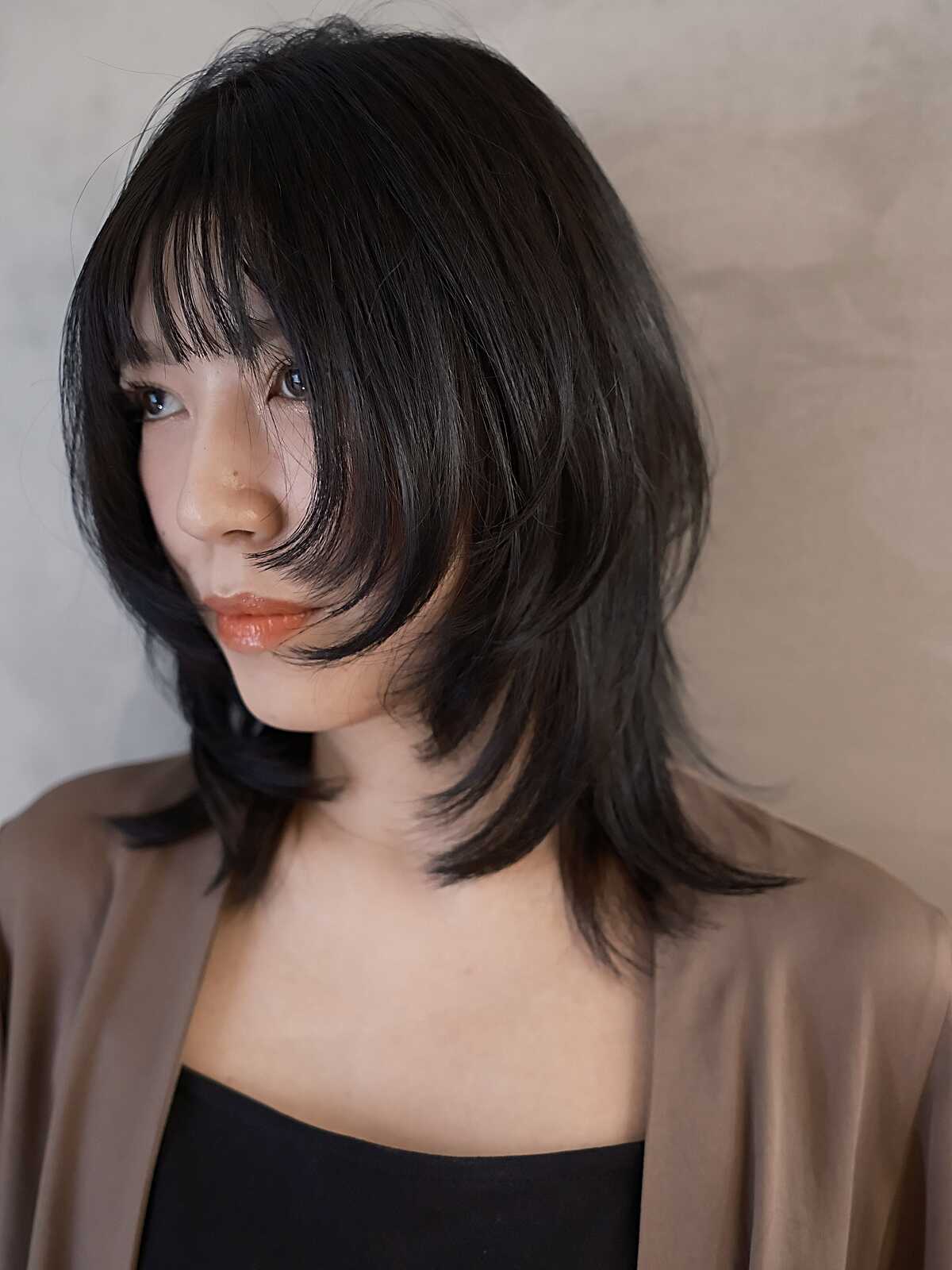 Choppy black medium shag cut with heavy straight bangs