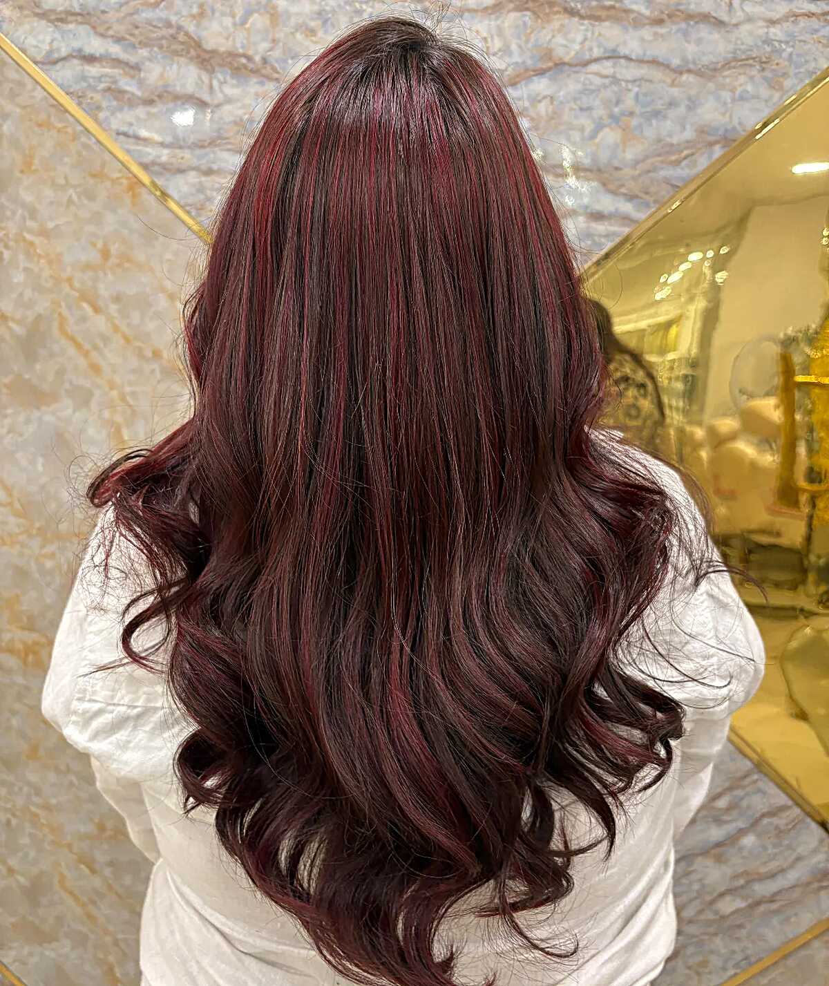 Long dark burgundy brown hair with red highlights and curls