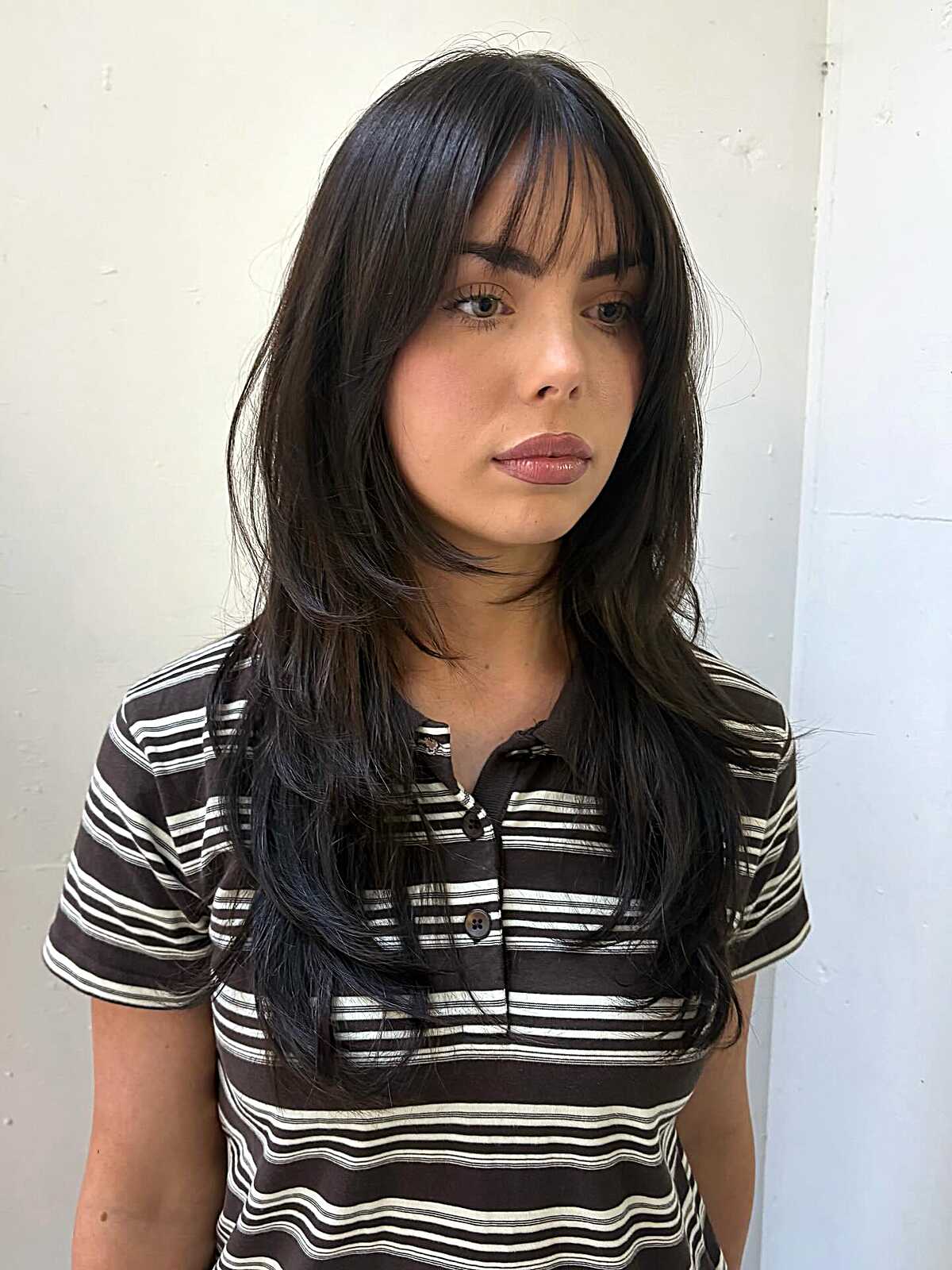 Long dark hush cut with soft arched bangs and layers