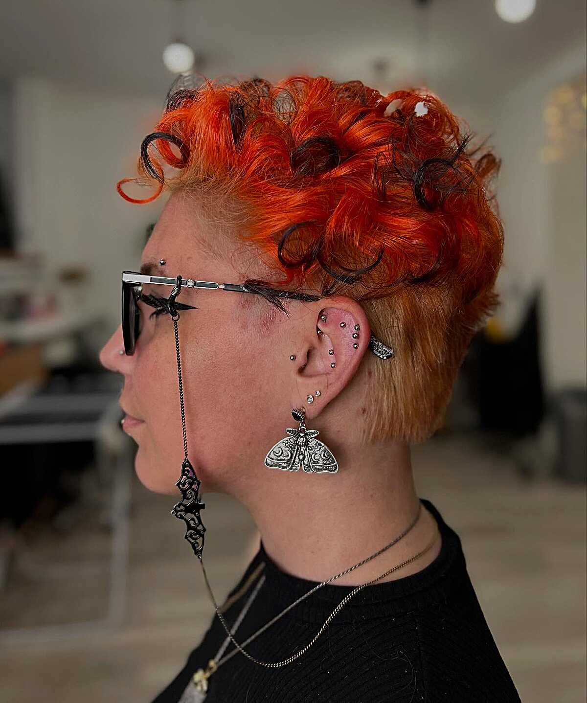 Electric orange curly top with buzzed sides and glasses