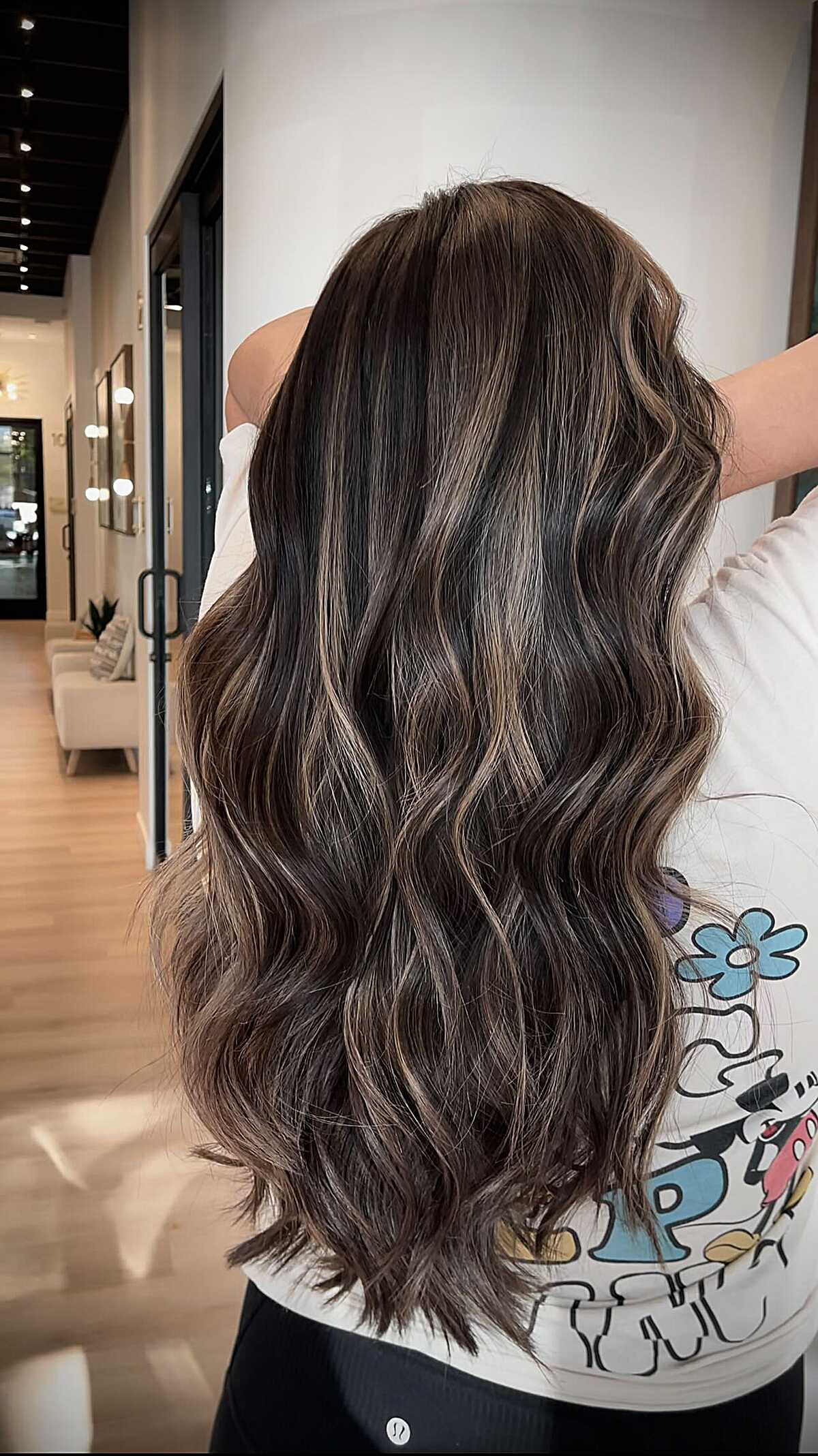 Long dark hair with polished waves and subtle ash ribbons