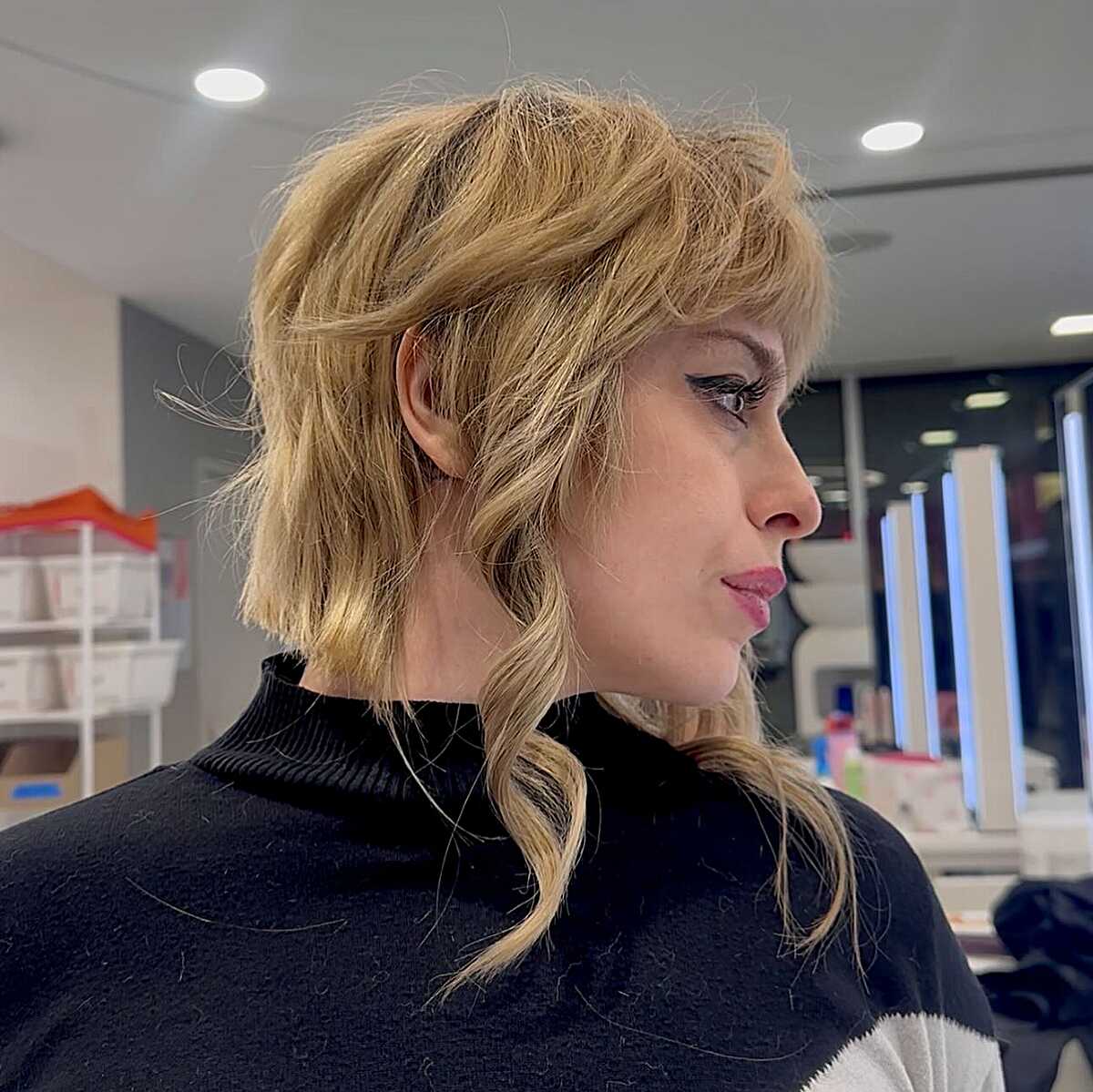 Side profile of warm blonde wavy shag with wispy bangs