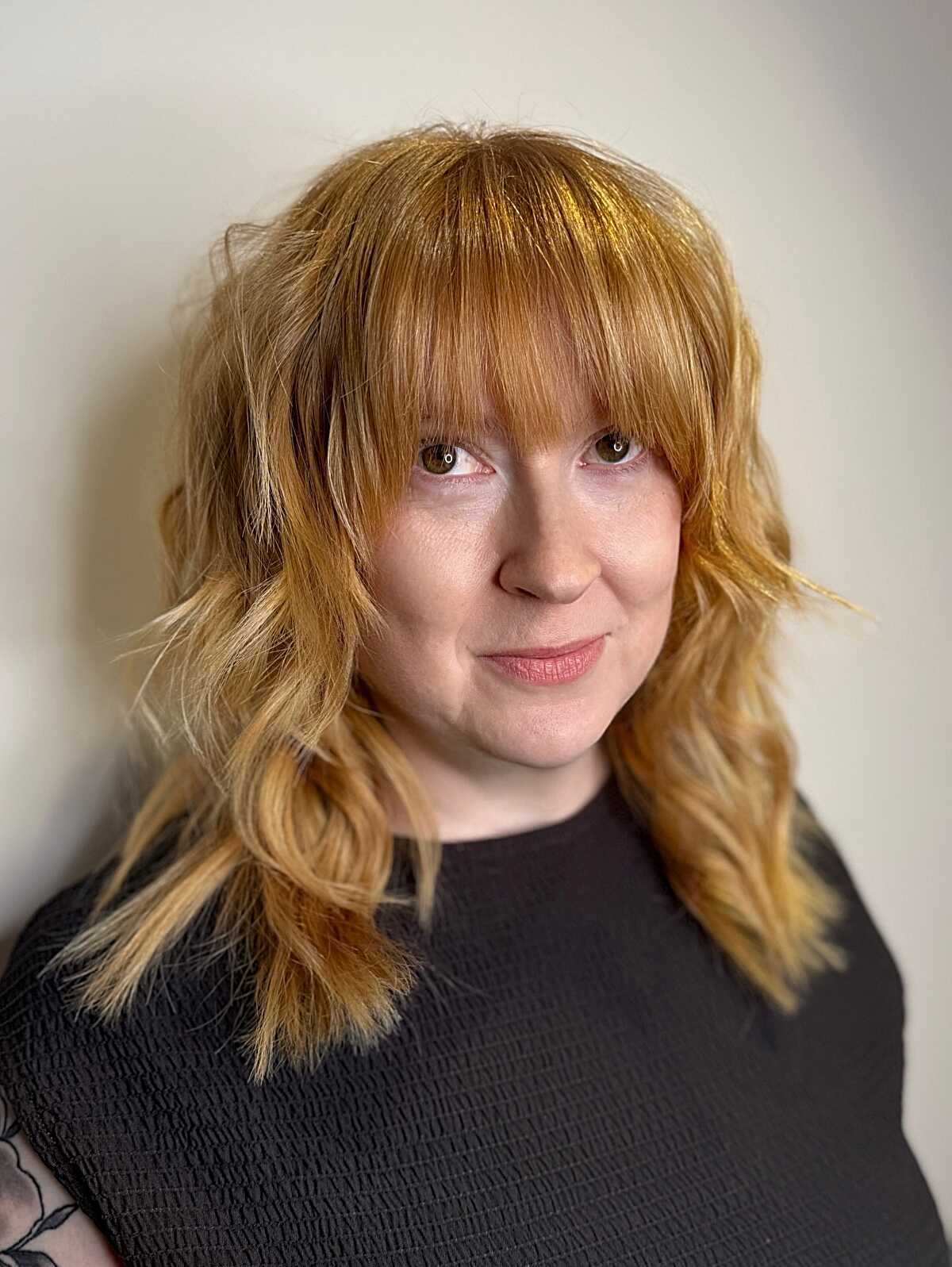 Medium strawberry blonde shag with full bangs and waves