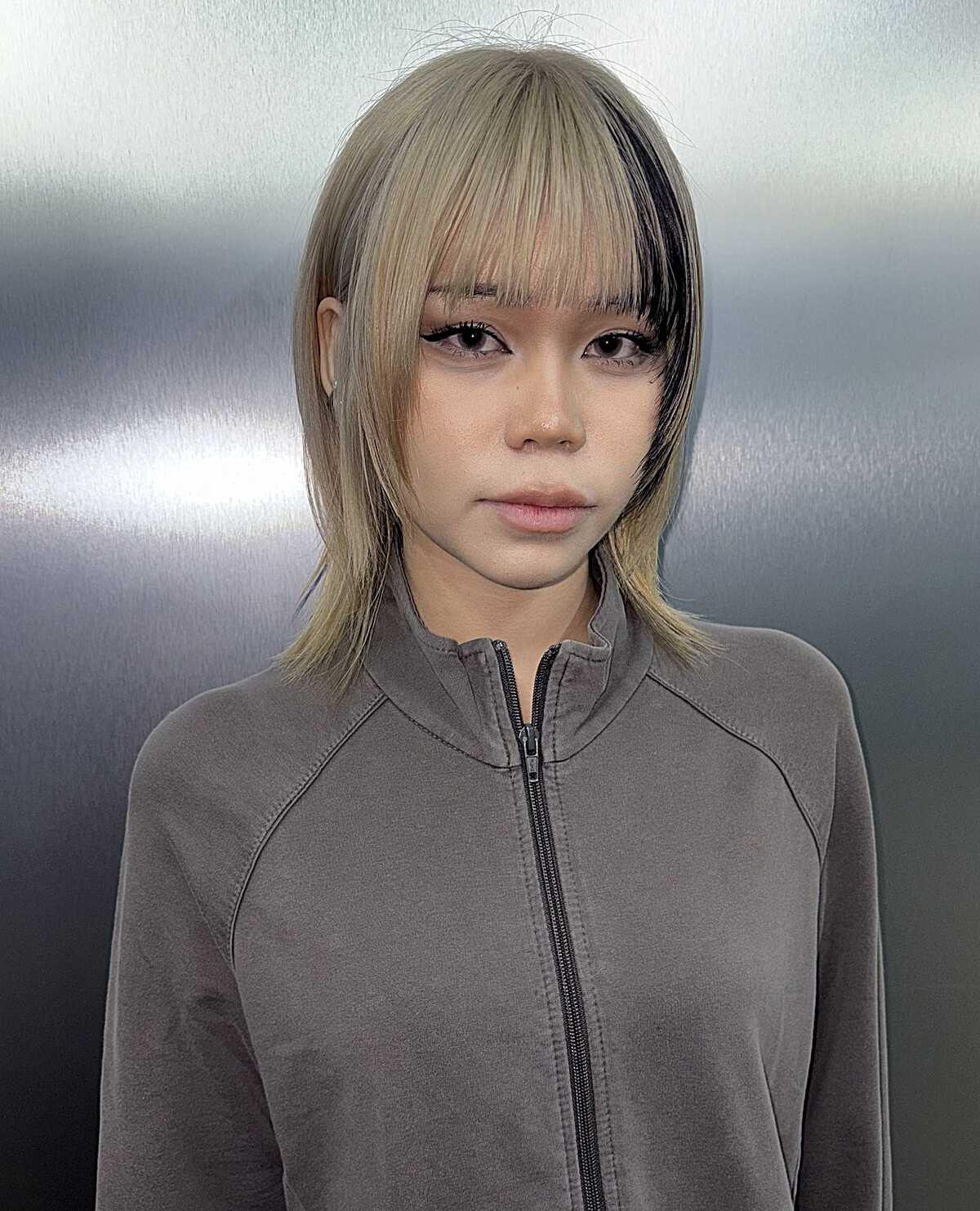 Chin-length blonde bob with a black streak near the ear