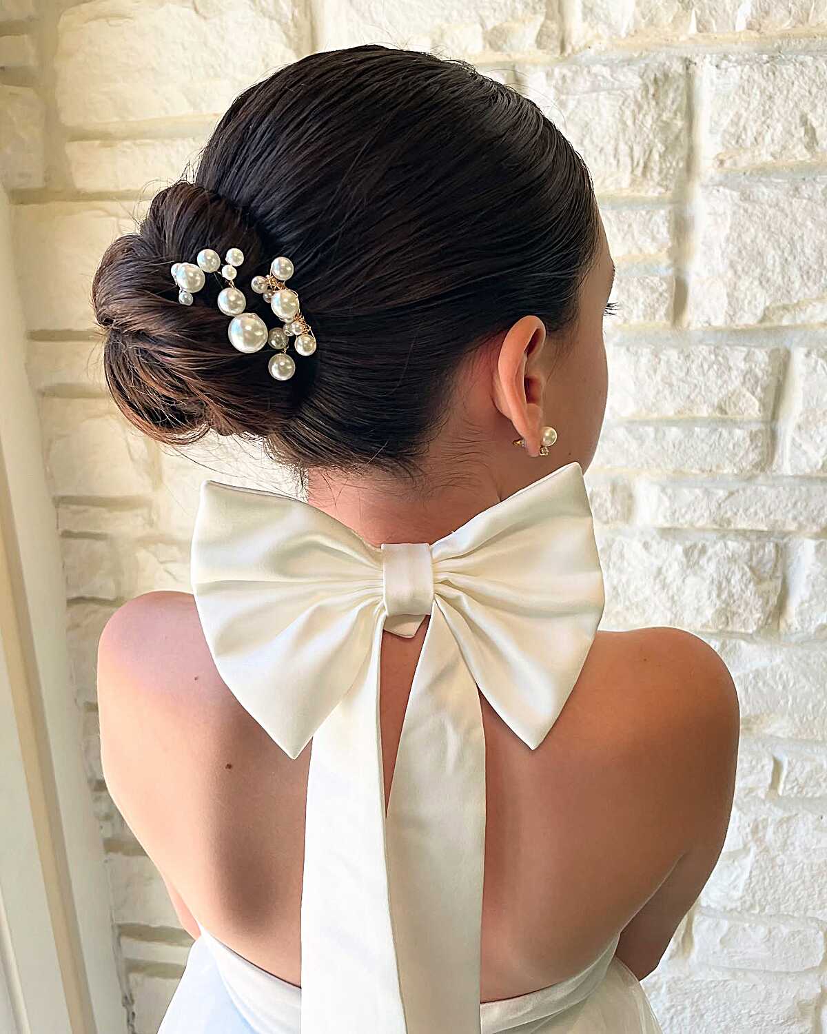 Sleek low chignon with large pearl cluster hair comb