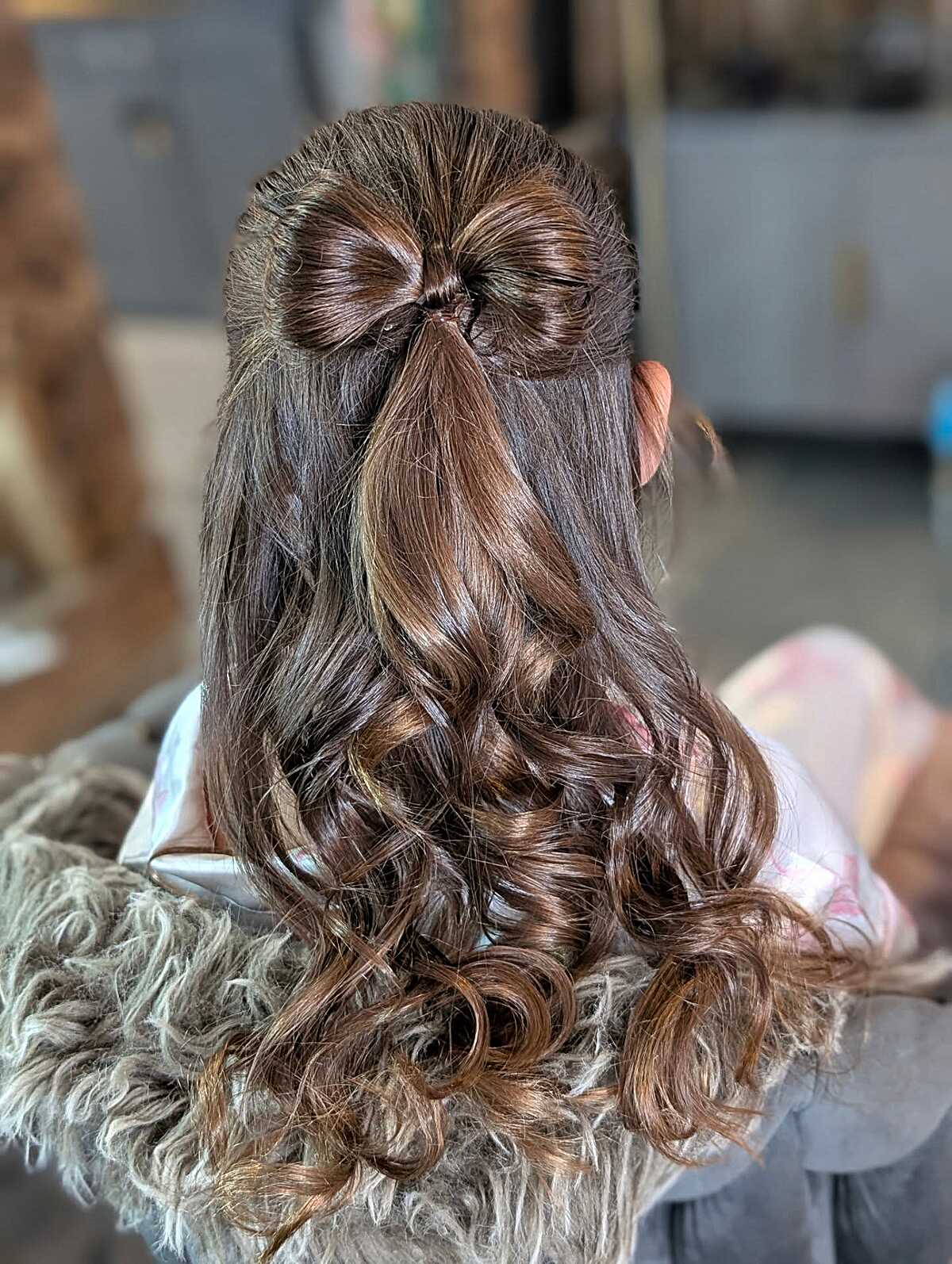 Half-up hairstyle with hair shaped into a bow and curls
