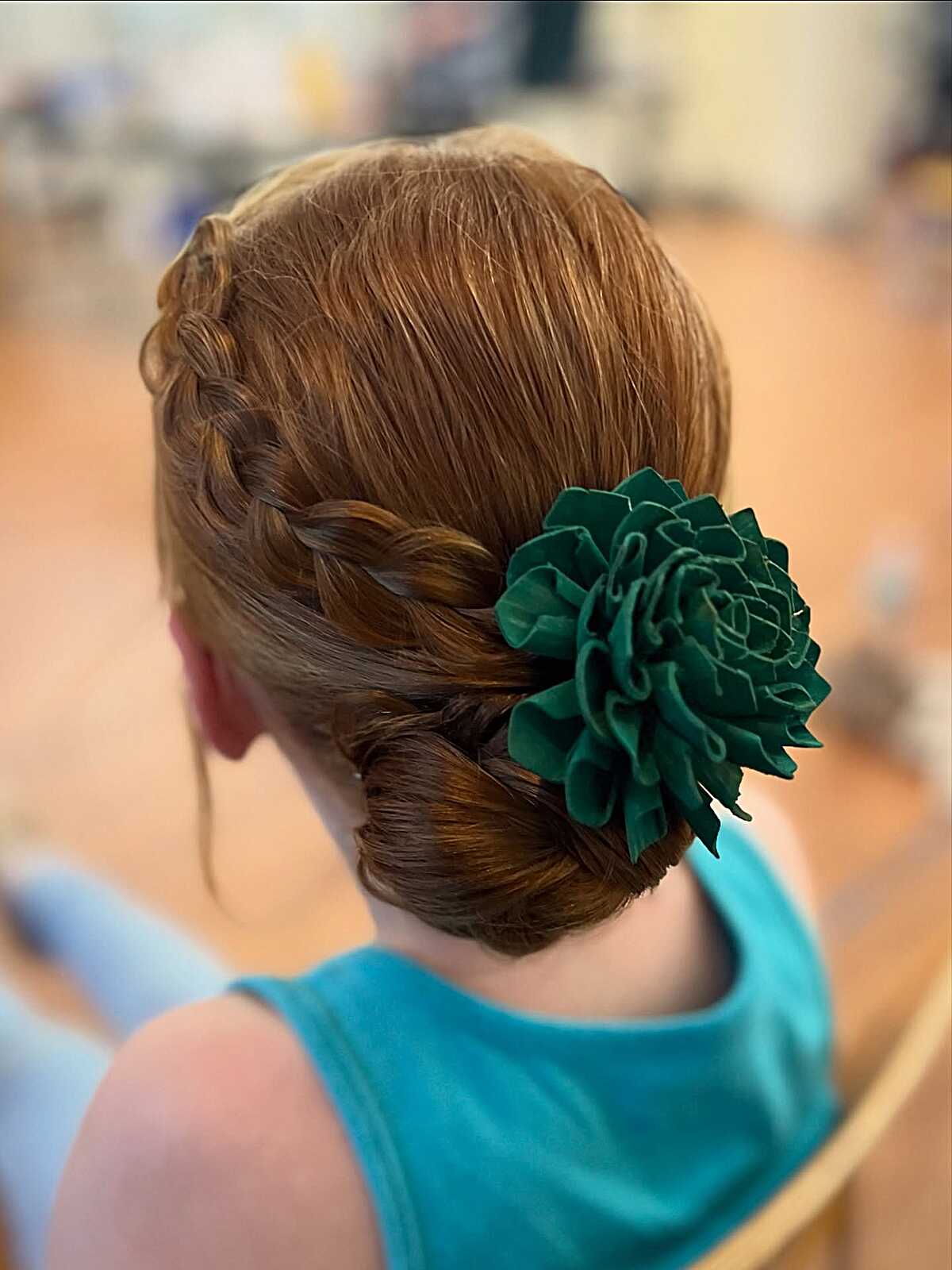 Side French braid low bun with large green fabric flower