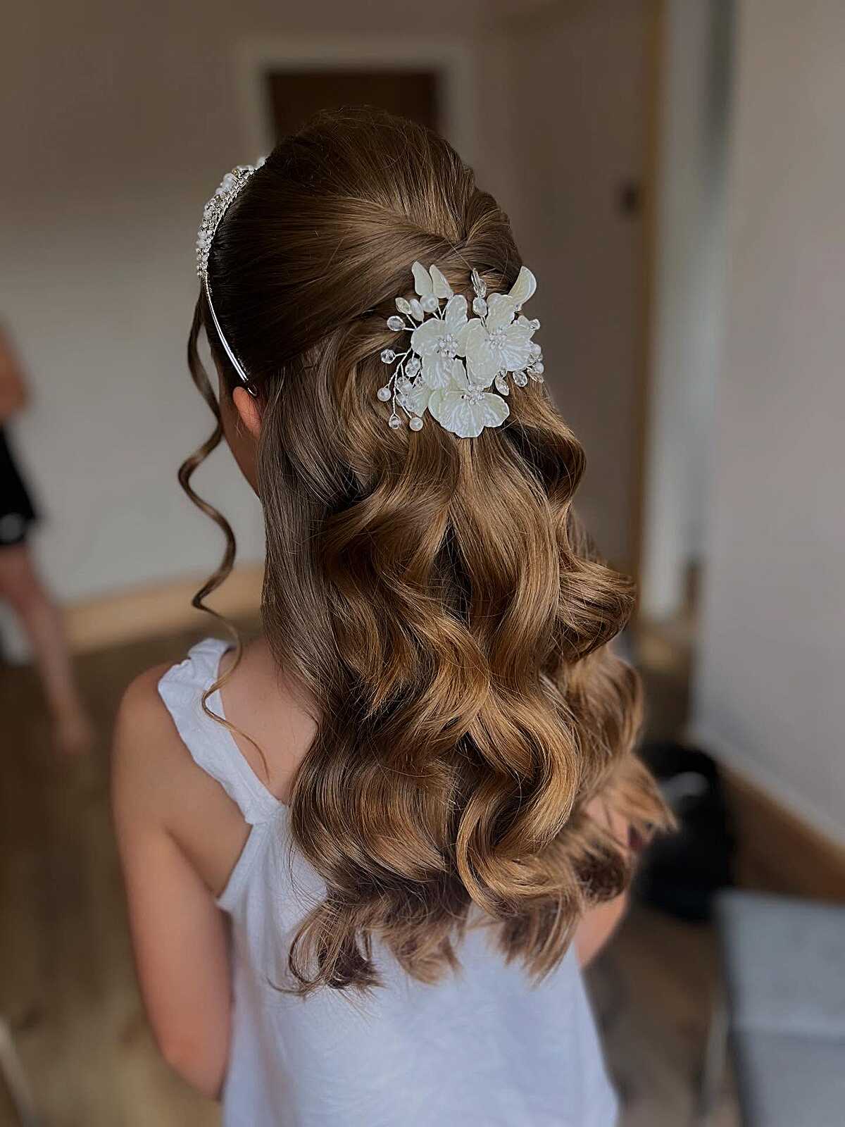 Polished half-down with tiara, floral clip, and bouncy waves