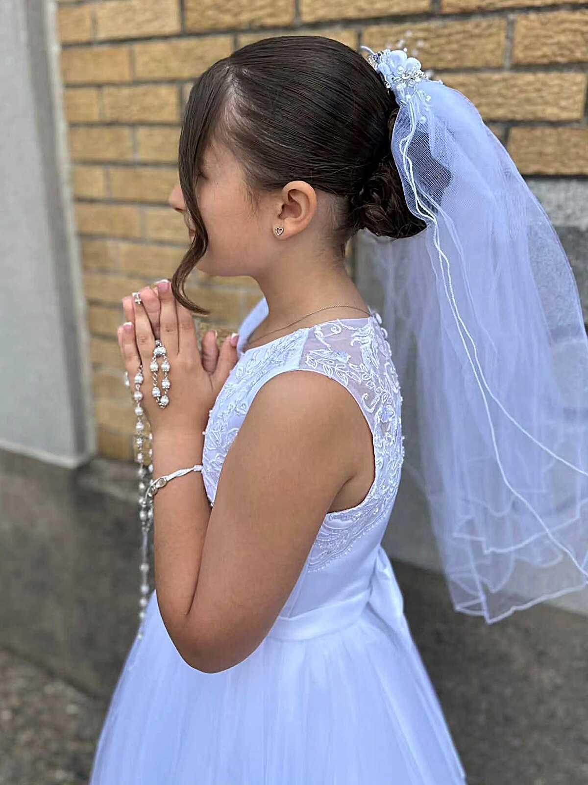 Simple low bun with white veil and single curled tendril