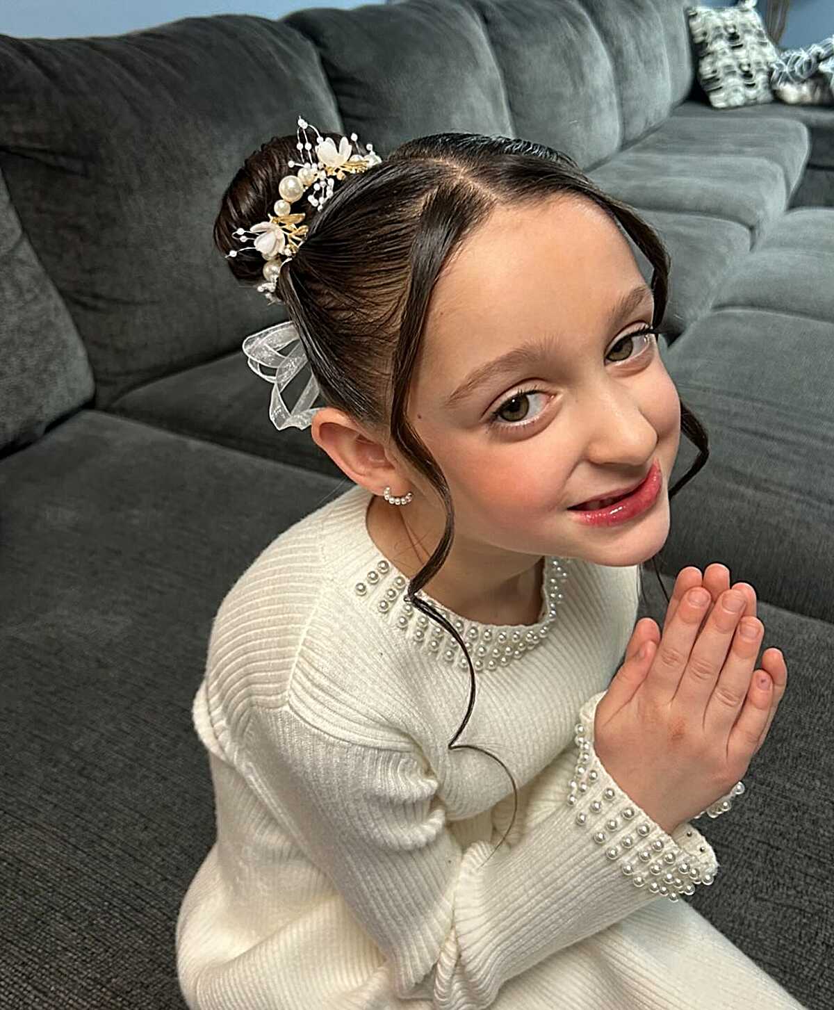 Sleek low bun with pearl floral comb and face-framing curls