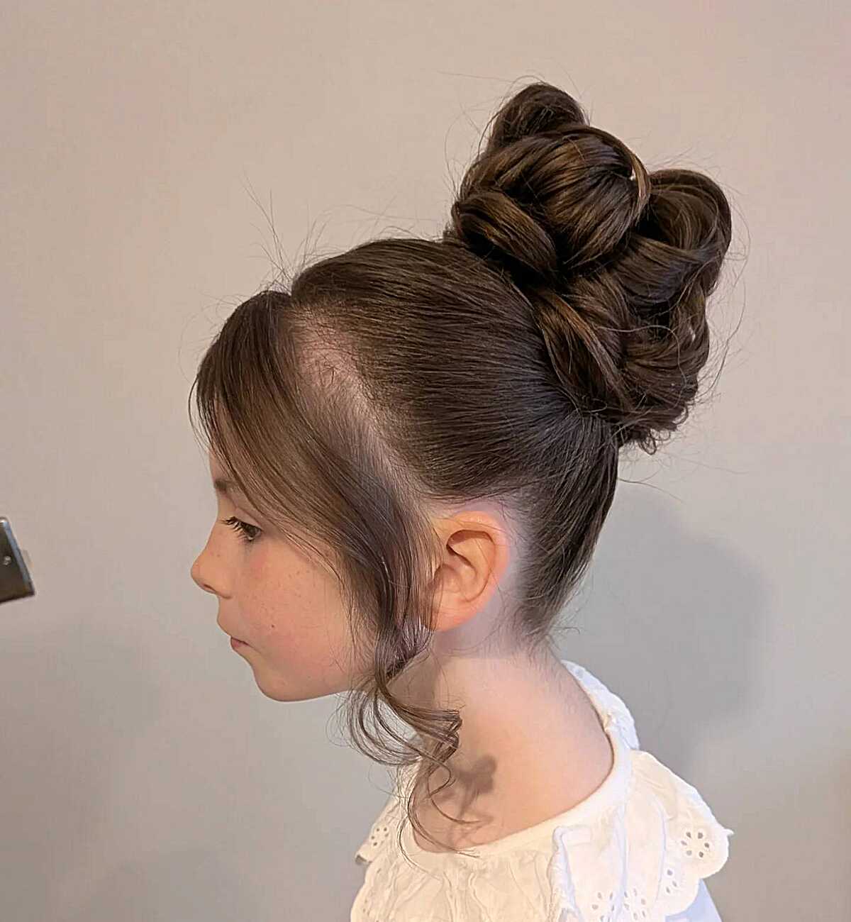 High textured bun with loose face-framing wisps on a girl