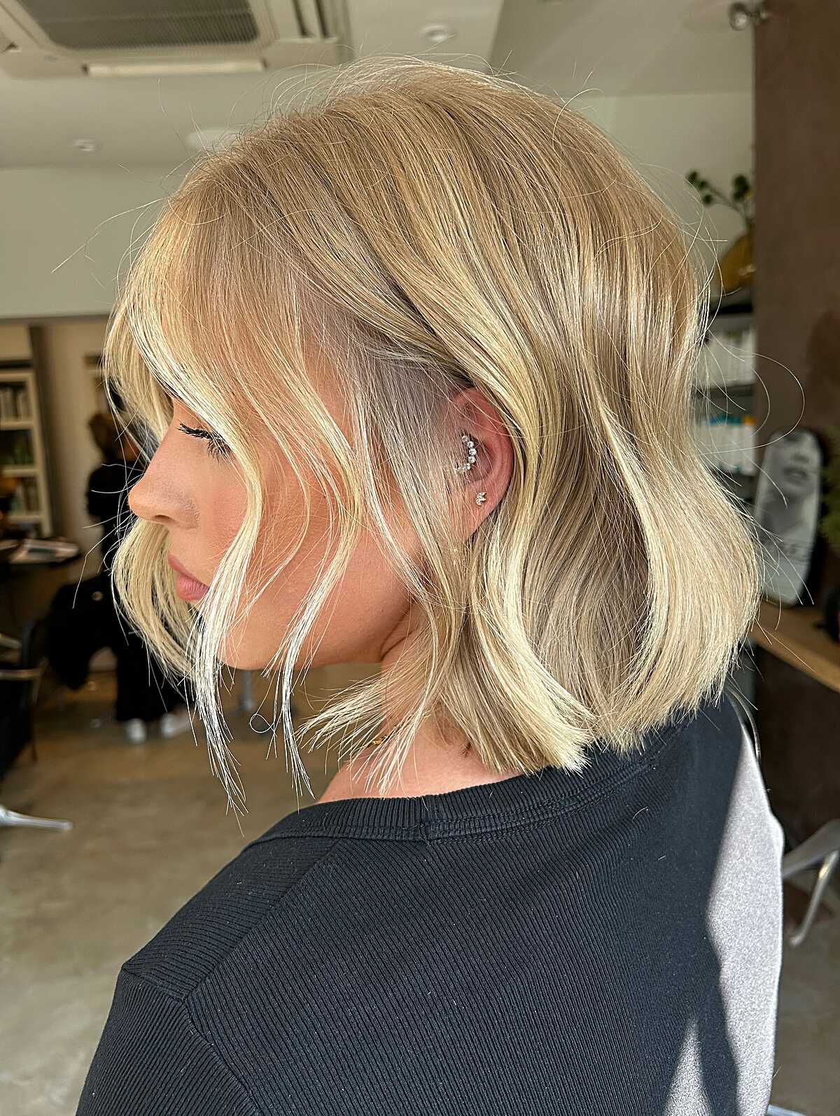 Buttery blonde wavy bob with curtain bangs side view